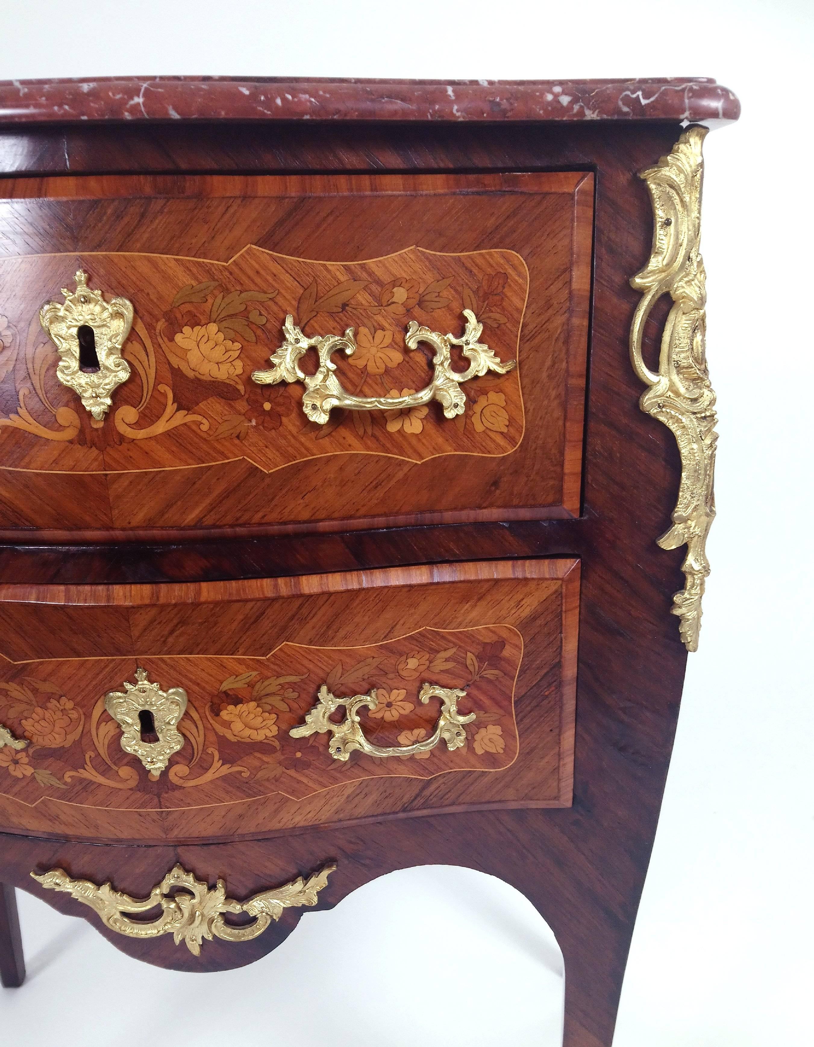 This beautiful and more sought-after size French bombe shaped commode features delicately detailed marquetry inlay work of scrolls and floral designs. The chest also has superb ormolu mounts, decorative vine shaped pull handles and ornate