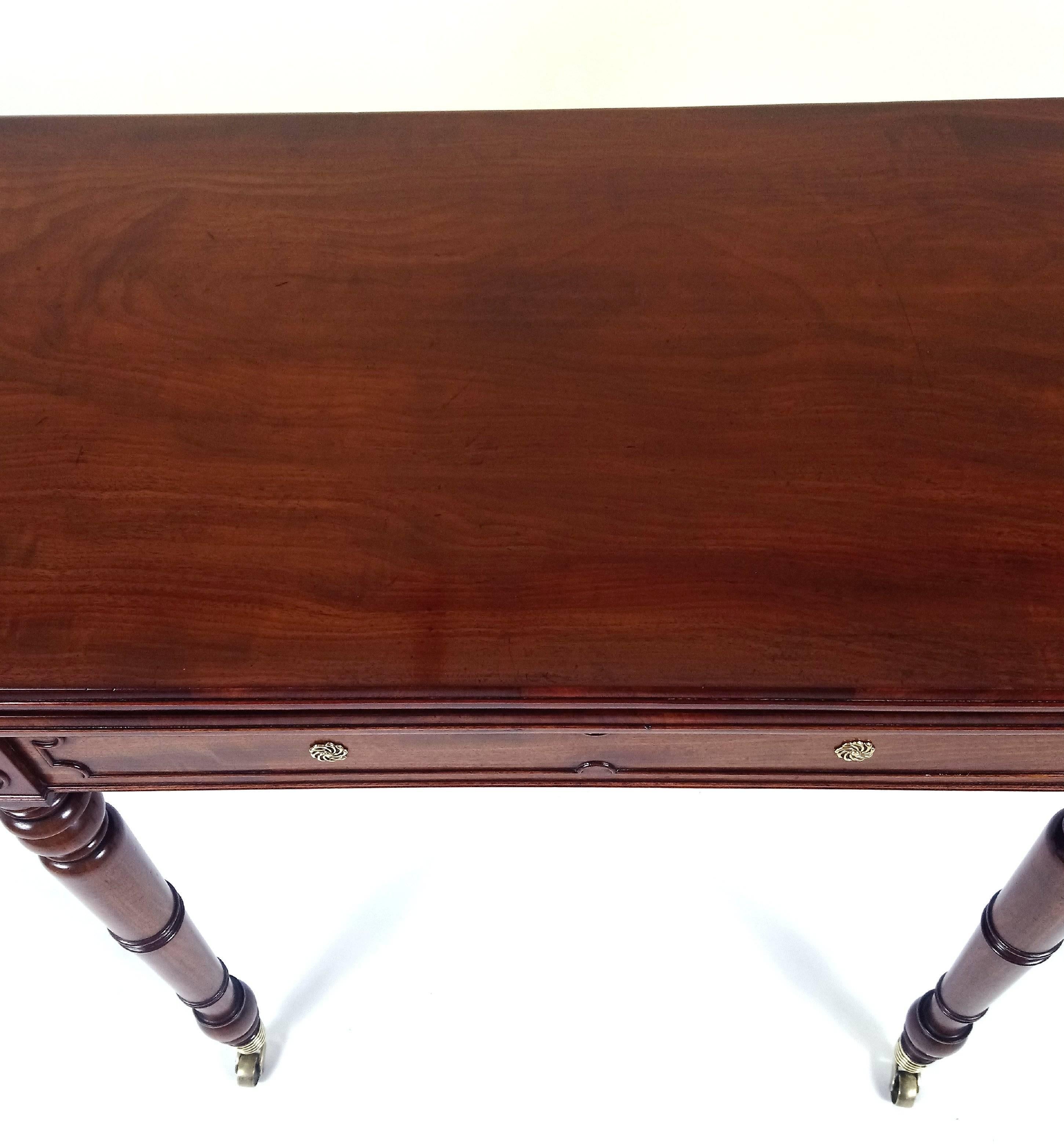 This very handsome and fine quality Regency mahogany fold over games table is in the manner of Gillows and features molded decoration, set with brass rosettes on well-turned supports ending with the original beehive brass castors. The table measures