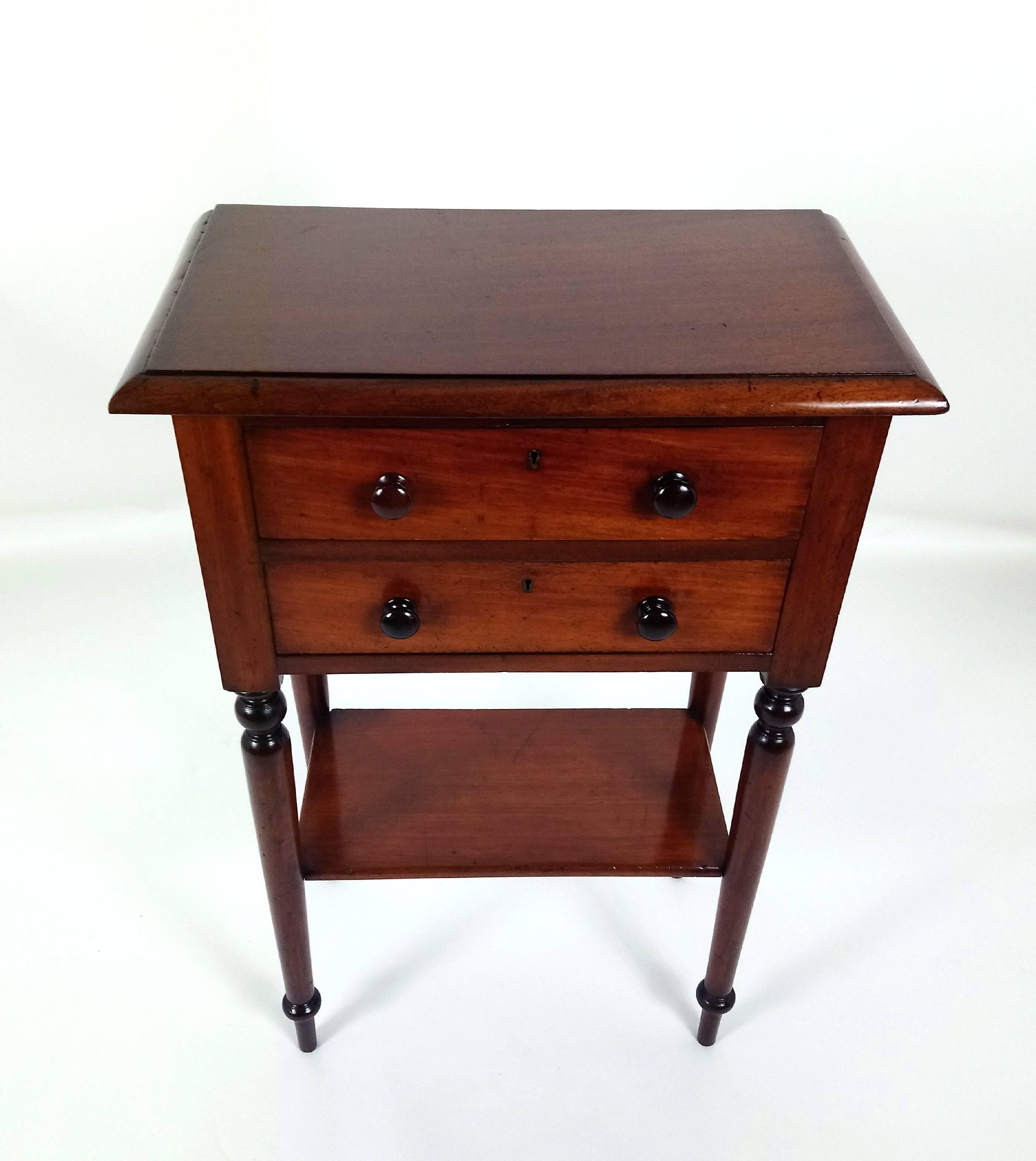 This charming and well-proportioned late Victorian English mahogany hall table is fitted with 2 top drawers on turned slender supports with an under tier shelf. The brass lock is stamped Hamptons, an English Locksmith of the period. It measures 23 ¼