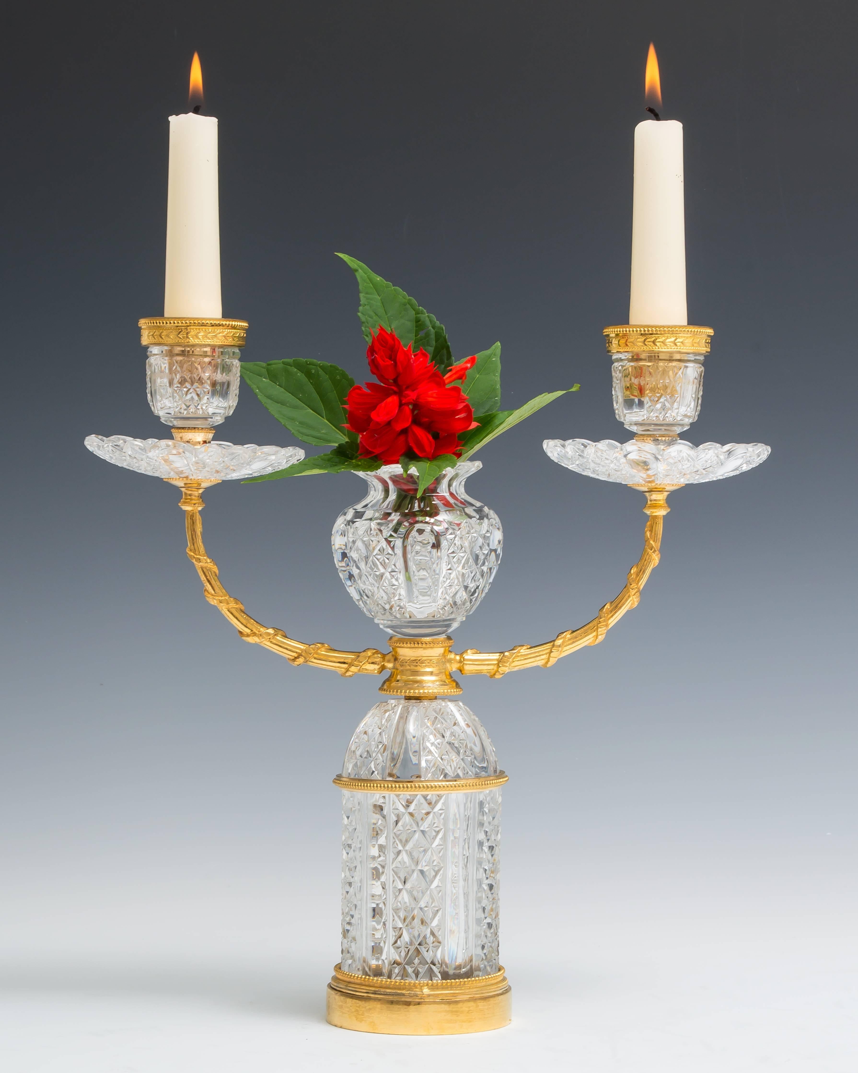 A pair of cut-glass and ormolu candelabra by F&C Osler the drum base cut with alternate pillar and star cut diamond panels issuing two arms terminating with drip pans and ormolu mounted candle nozzles with the same cutting the centred with a posy
