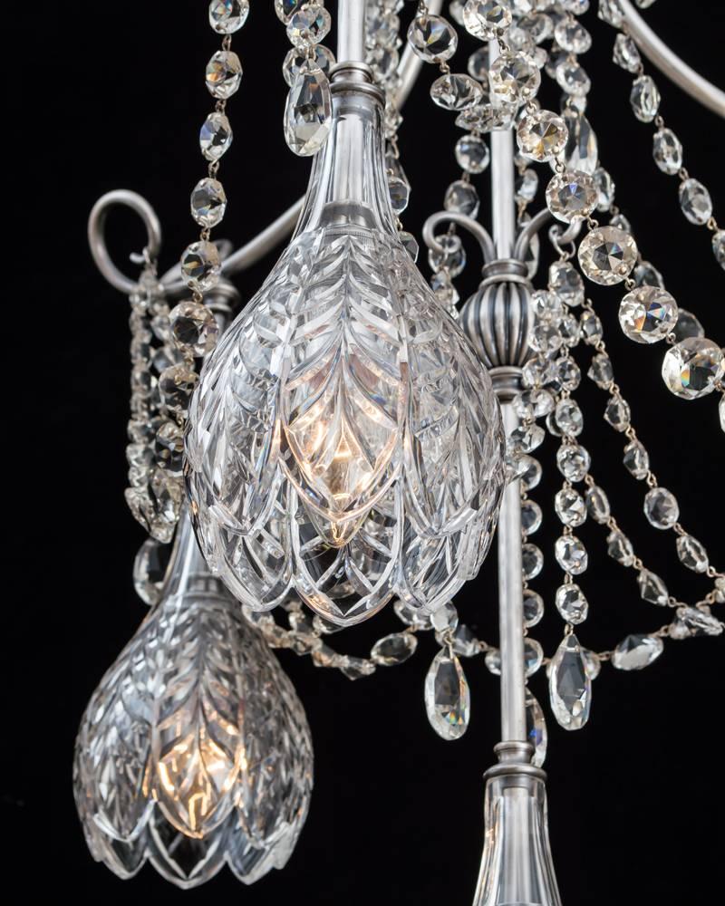 The electrolier of unusual form having silver plate struts surmounted with four scalloped edge feature cut shades down facing, the fitting hung with cascading swags of flat back spangles and pear shaped finials.