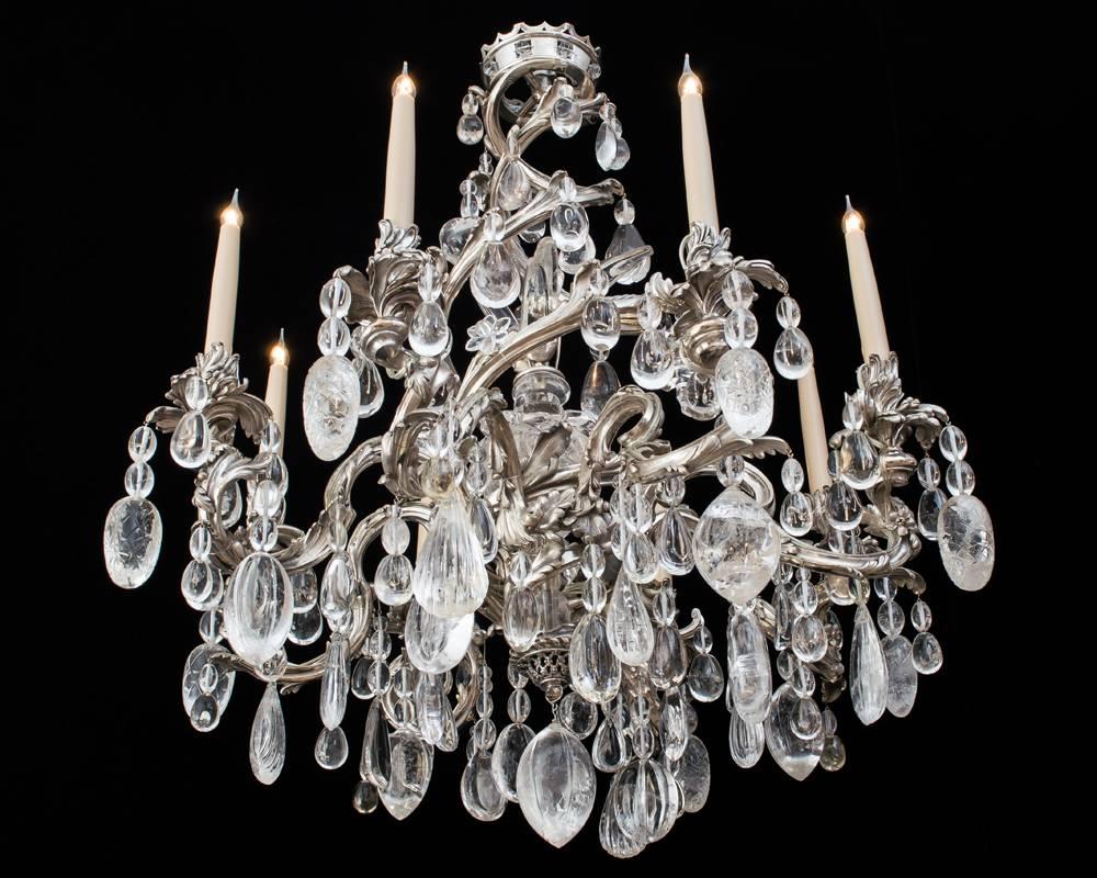 A highly unusual silver bronze chandelier constructed with eight scroll leaf arms supporting candle nozzles and drip pans suspended on two spiralled vines from the top crown the centre with rock crystal shaft mounted with crystal reeds and leafs the
