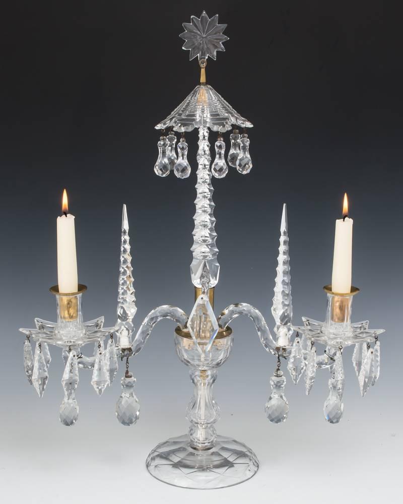 A rare pair of George II English cut-glass two-light candelabra attributed to Christopher Haedy the diamond-cut bases with baluster stem and all in one containers these centred by triangularly notched spires these surmounted by a drop hung step cut