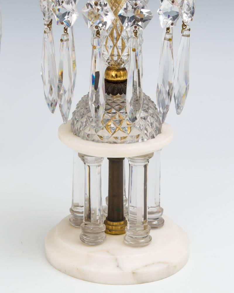 A rare pair of Regency temple of love candlesticks unusually on marble bases with five glass columns supporting diamond cut eggs, drip pans and candle nozzles hung with double cut star buttons and icicles.
