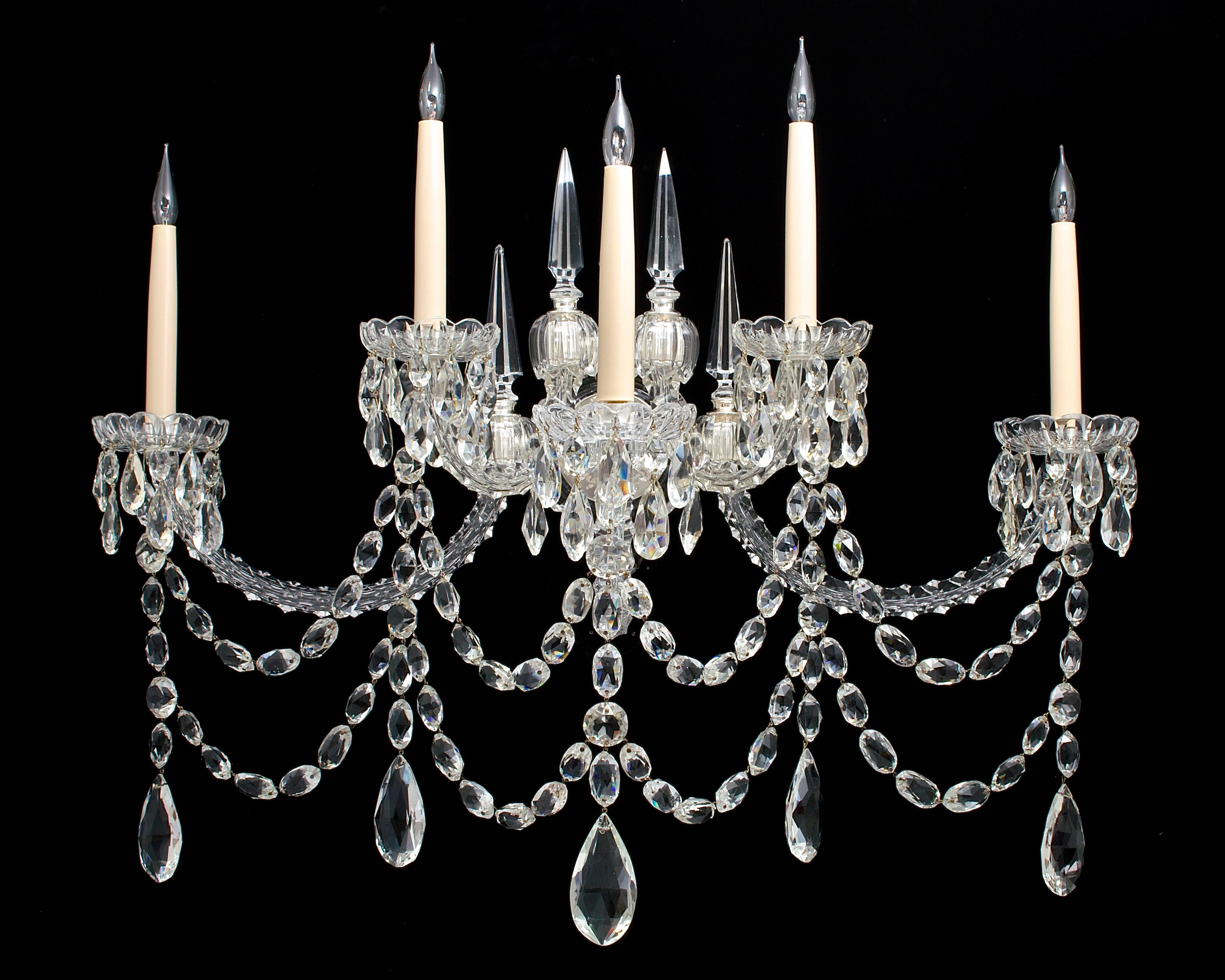 An unusual pair of mid-Victorian five-light cut-glass silver mounted wall-lights (original for gas) the silvered glass covered back plates supporting five half hoop candle arms arranged on two levers these arms with drop hung thumb cut drip pans and