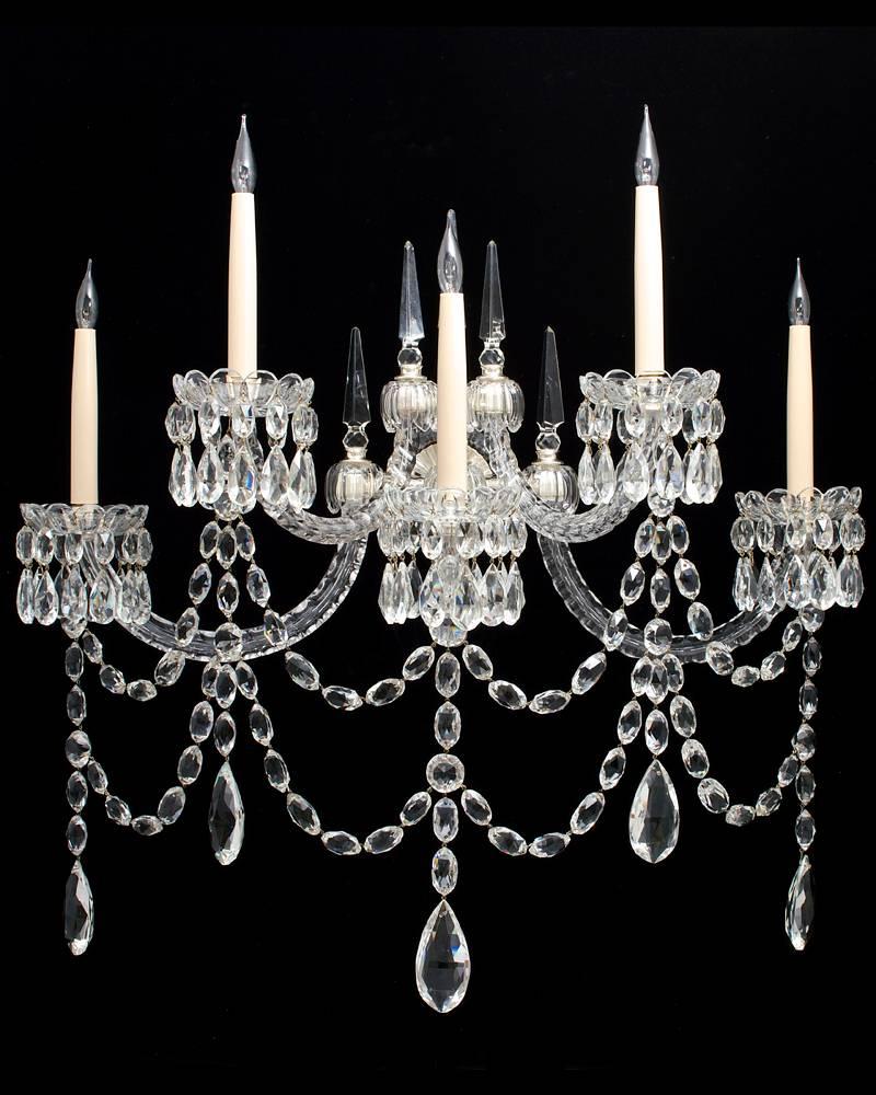 An unusual pair of mid-Victorian five-light cut-glass silver mounted wall-lights (original for gas) the silvered glass covered back plates supporting five half hoop thumb cut candle arms arranged on two levers these arms with drop hung thumb cut
