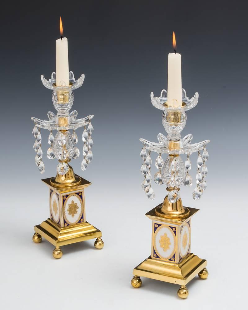 Ein Paar georgianische Kerzenständer auf quadratischen, vergoldeten Sockeln mit Kugelfüßen, die quadratische Porzellantrommeln mit blauem und vergoldetem Dekor tragen. Diese tragen geschliffene Glaseier, die mit Van-Dyke-Pfannen und Düsen enden, die