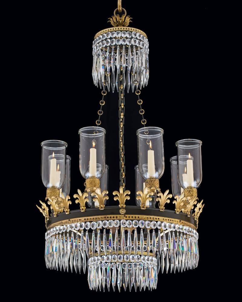 An Unusual Regency period eight-light gilt bronze chandelier the main bronzed band surmounted with eight glass hurricane shades these mounted in fine decorated mounts the band also supporting Classic fleur-de-lys anthemions and an unusual Gothic