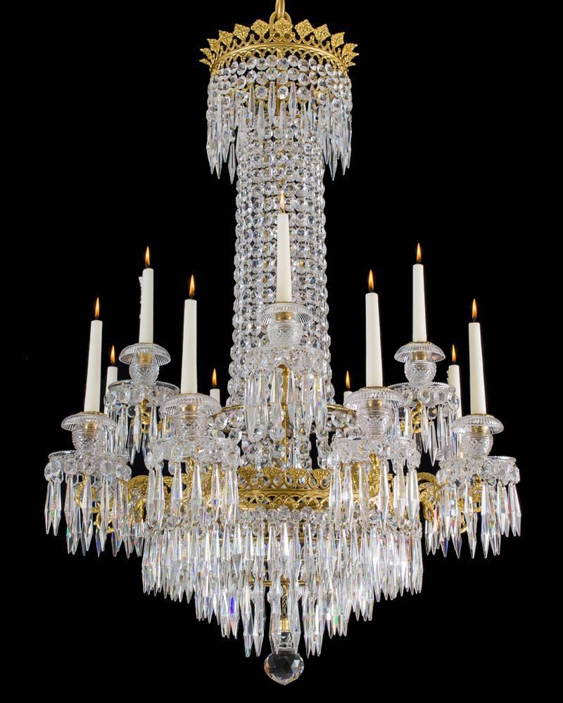 A fine Regency chandelier of classic tent and waterfall design arranged with two tires of lights the top tier having four lights and the lower eight lights each arm issuing a diamond cut drip pan and turnover nozzle and candle cup, The Fine main