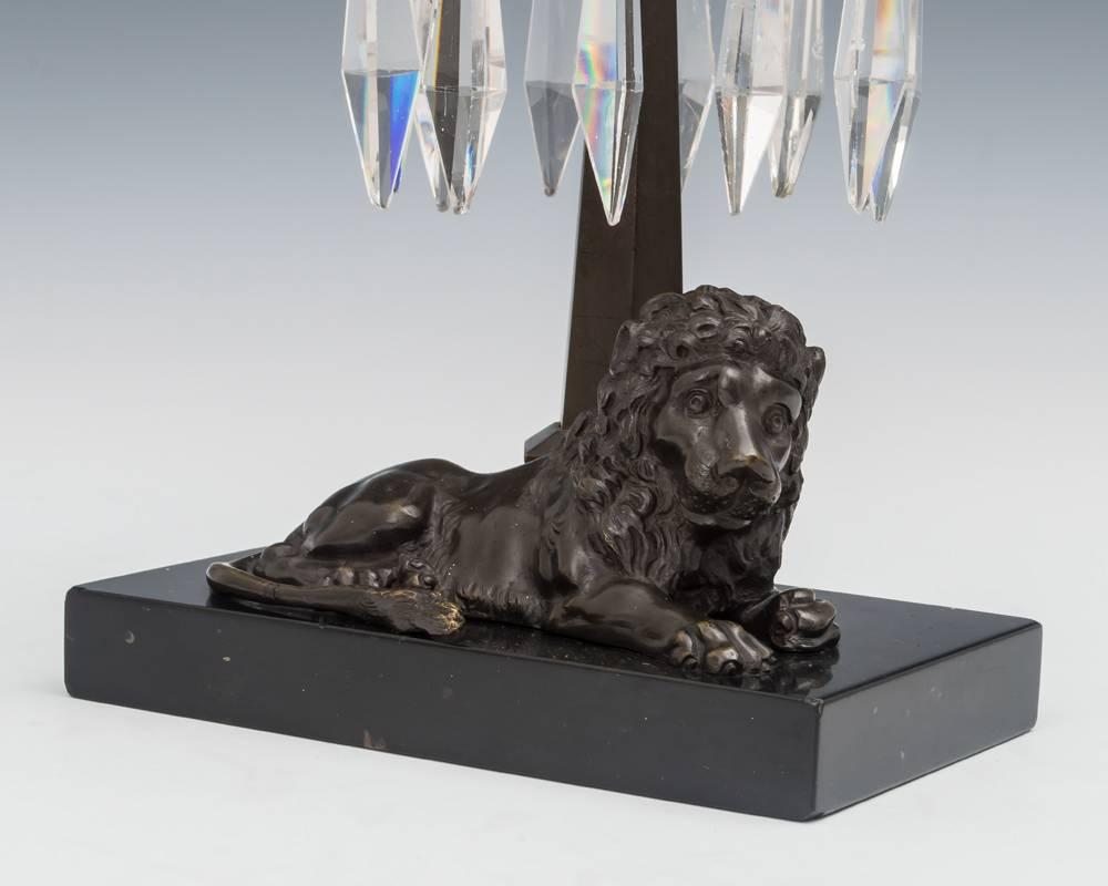 A unusual pair of bronze lion candlesticks on black marble base hung with triangular icicles.