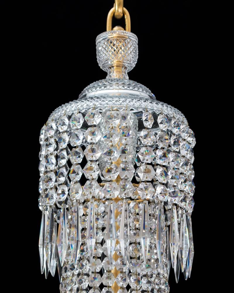 A fine regency chandelier of classic tent and waterfall design the main ormolu ring issuing eight j arms supporting diamond cut drip pans and candle nozzles the chandelier draped with star spangles and triangular icicles.
