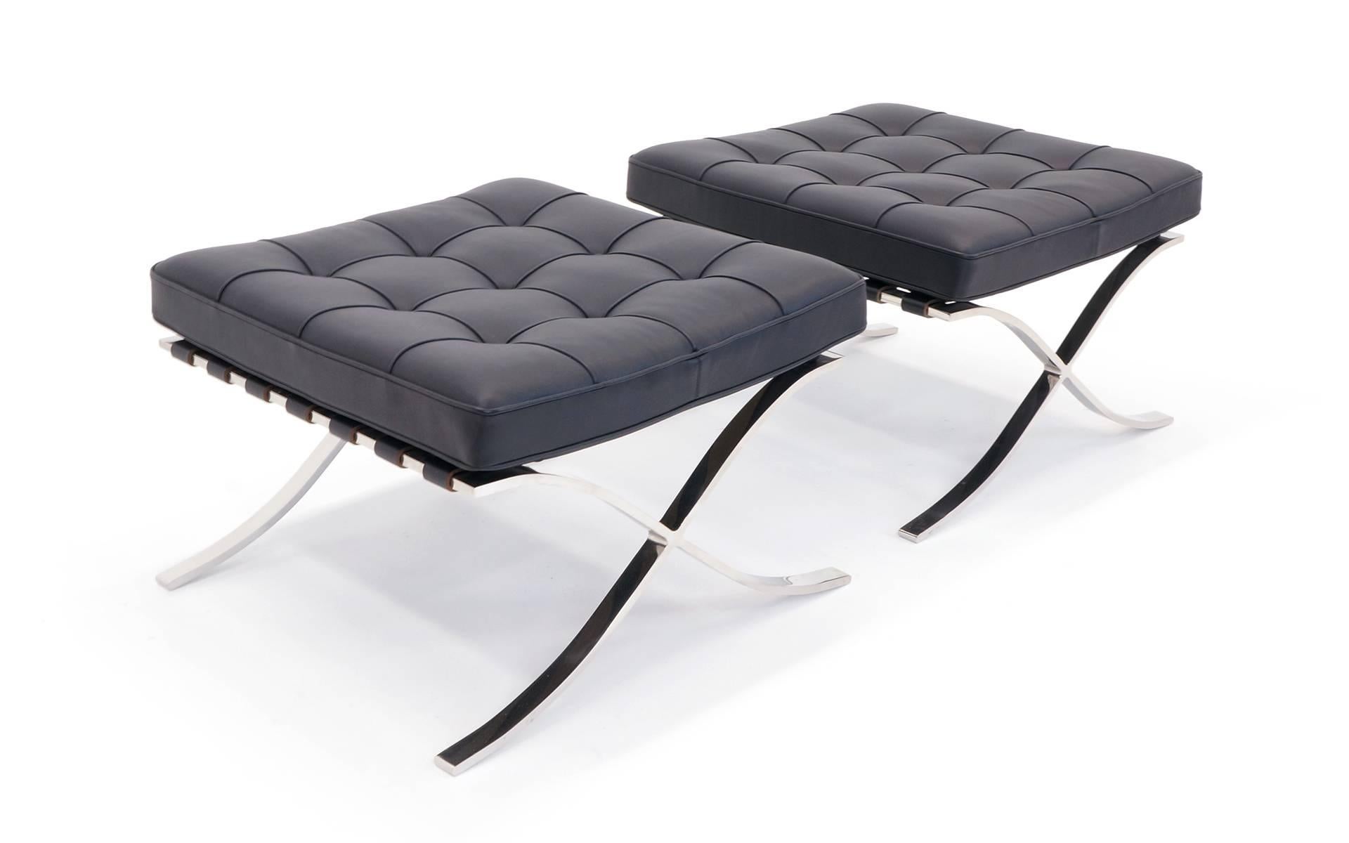 Virtually mint condition pair of Knoll Barcelona ottomans. These are the more expensive solid stainless steel (not chromed steel) version that costs about $10,000 for a new pair.  Use as an ottoman stool or bench. Classic black leather.  Signed with