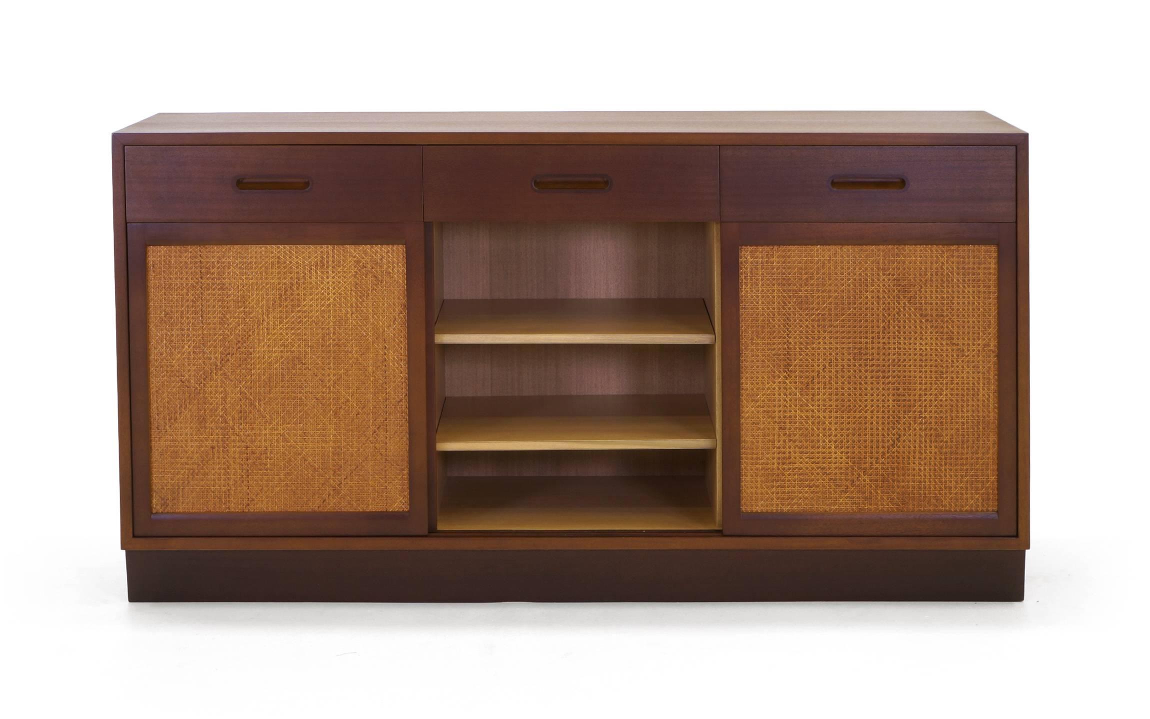 Edward Wormley storage cabinet / credenza. Three sliding cane panels reveal drawers and adjustable shelves. Expertly refinished and restored. 
 Excellent condition.
