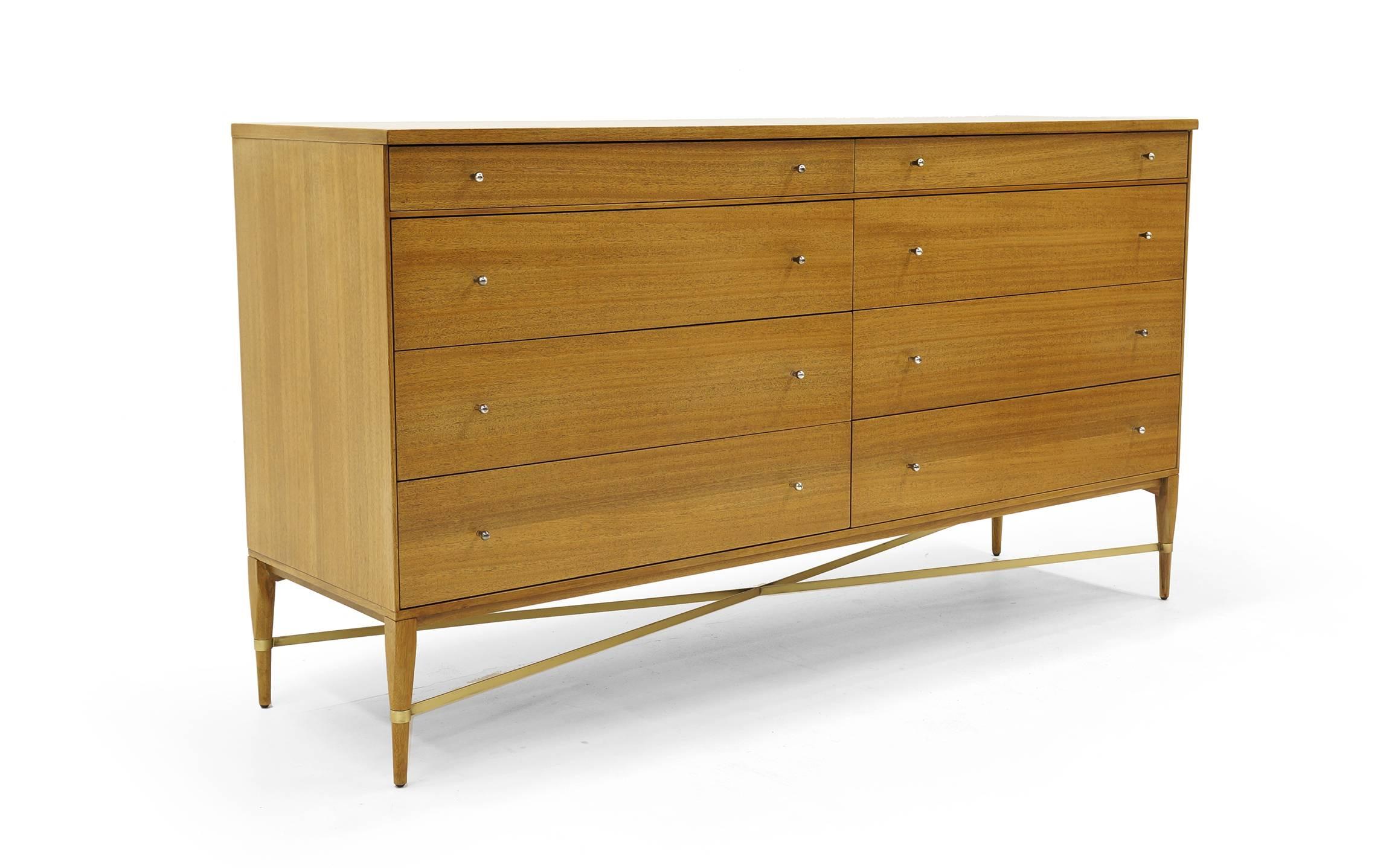 Paul McCobb for Calvin eight-drawer dresser with original pulls and brass cross stretchers. Bleached ribbon mahogany. Expertly refinished and restored to it's original finish. Really a beautiful cabinet.