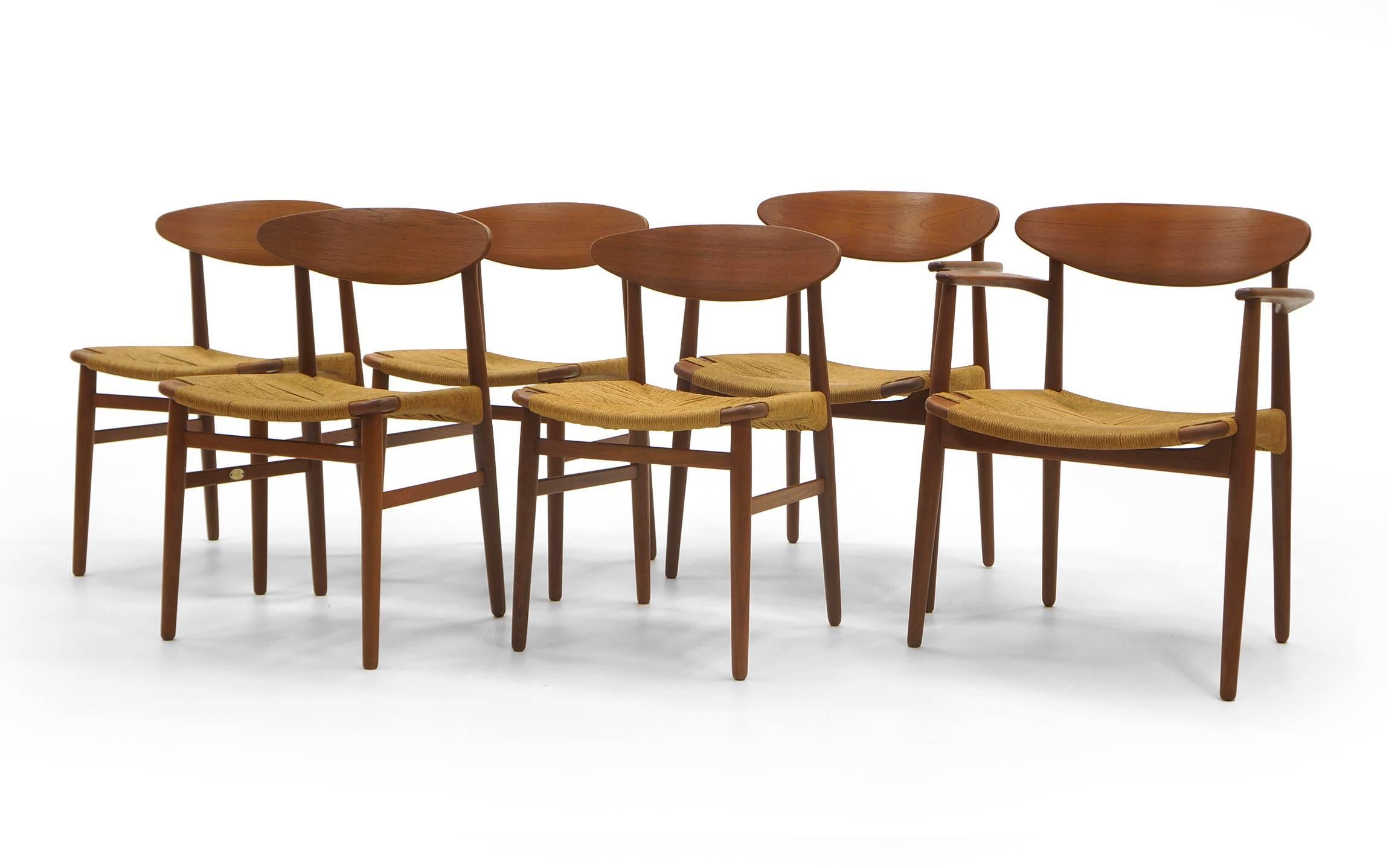 Set of six teak dining chairs with original woven grass rope seats designed by Ejner Larsen and Aksel Madsen for Naestved Mobelfabrik. Two armchairs and four side chairs. The frames have been expertly restored and refinished, the rope seats have
