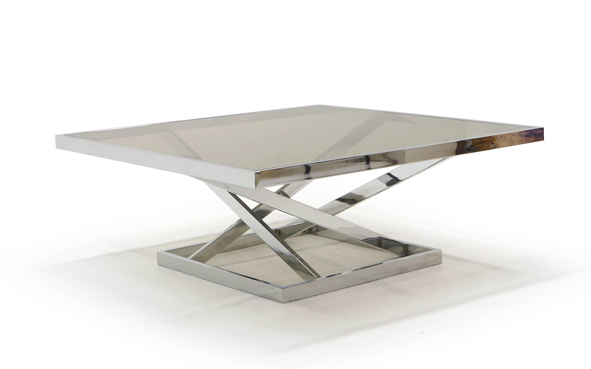 Square chrome and glass coffee table with a geometric angular shape to the base like none we have ever seen. The glass insets into the chrome frame. Very striking.