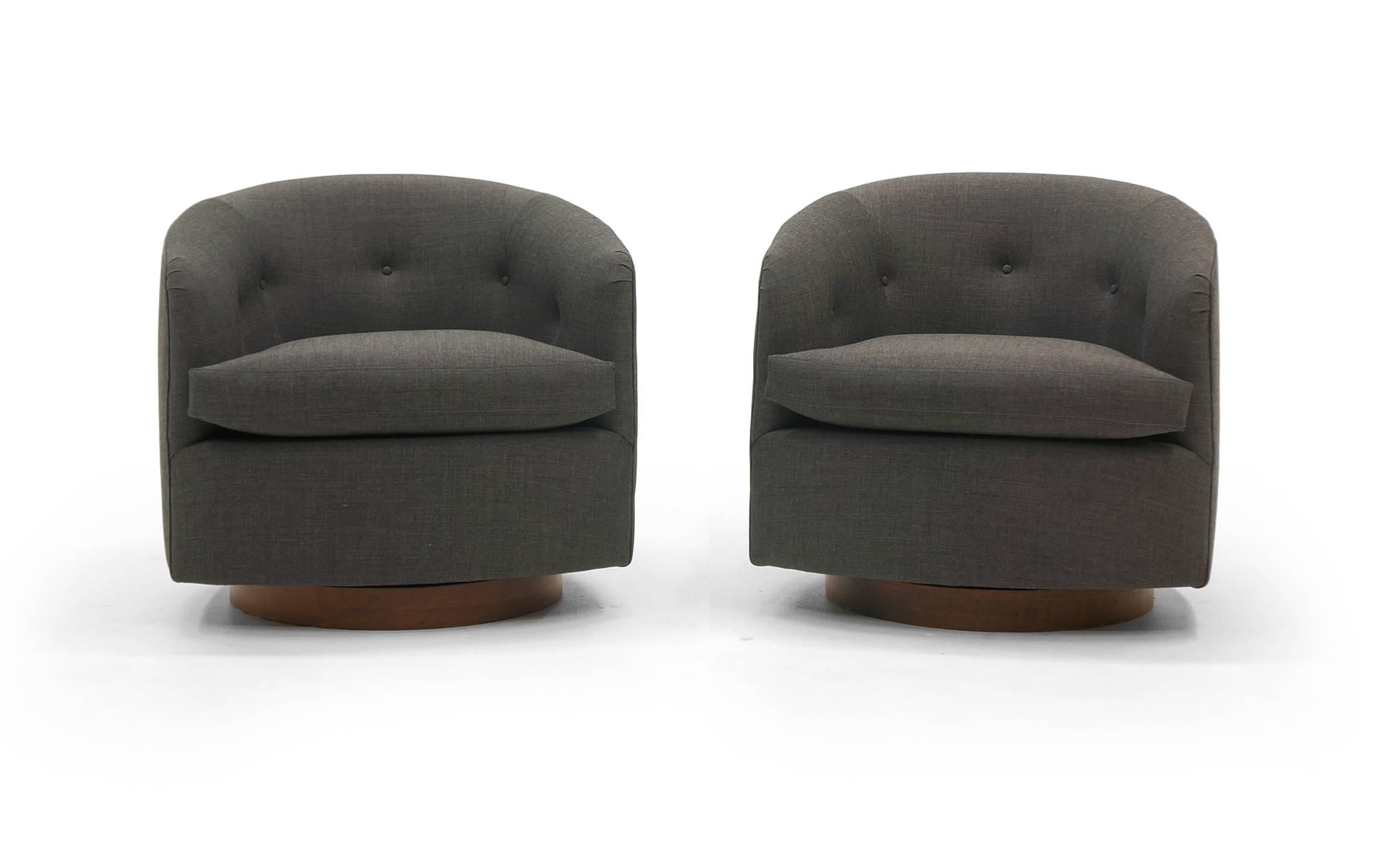 Stunning pair of Milo Baughman for Thayer Coggin's tilt and swivel even arm barrel chairs on walnut bases. These have been completely restored, refinished, and reupholstered in a beautiful charcoal gray / grey Maharam fabric (soft, durable wool).