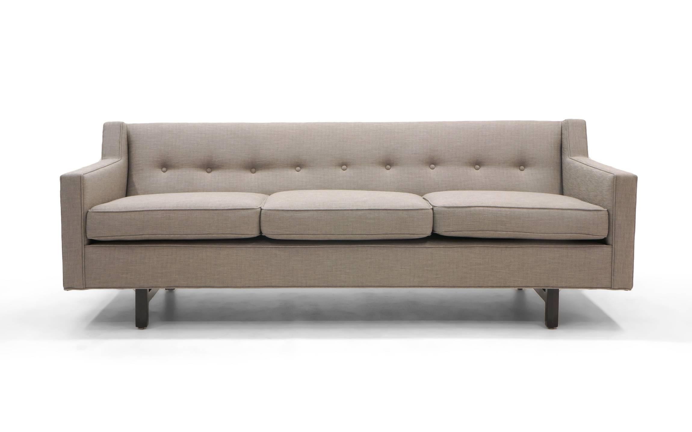 Classic Edward Wormley three-seat sofa. Fully restored and reupholstered in an elegant light gray / grey fabric. Buttoned back behind down filled loose cushions.
