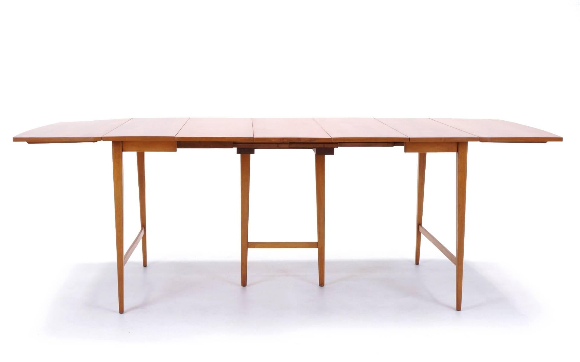 Paul McCobb drop leaf dining table with center legs for Winchendon Modern with three additional leaves. At its smallest, the table is 24 inch by 40 inch table for two. Each drop leaf is 15 inches so it extends to 39 inches with one leaf up and 54