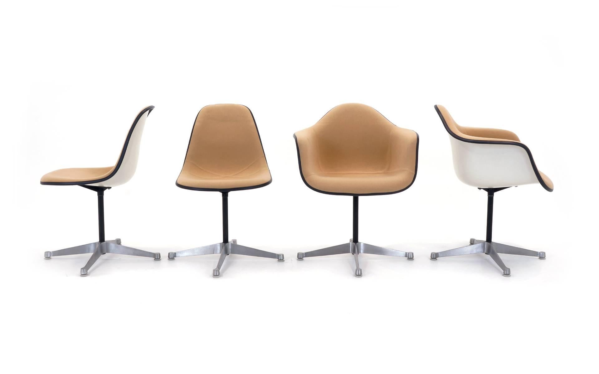 Set of eight Charles and Ray Eames fiberglass swivel chairs with cream colored upholstery. Two armchairs and six armless chairs all with the rare and desirable swiveling contract base.