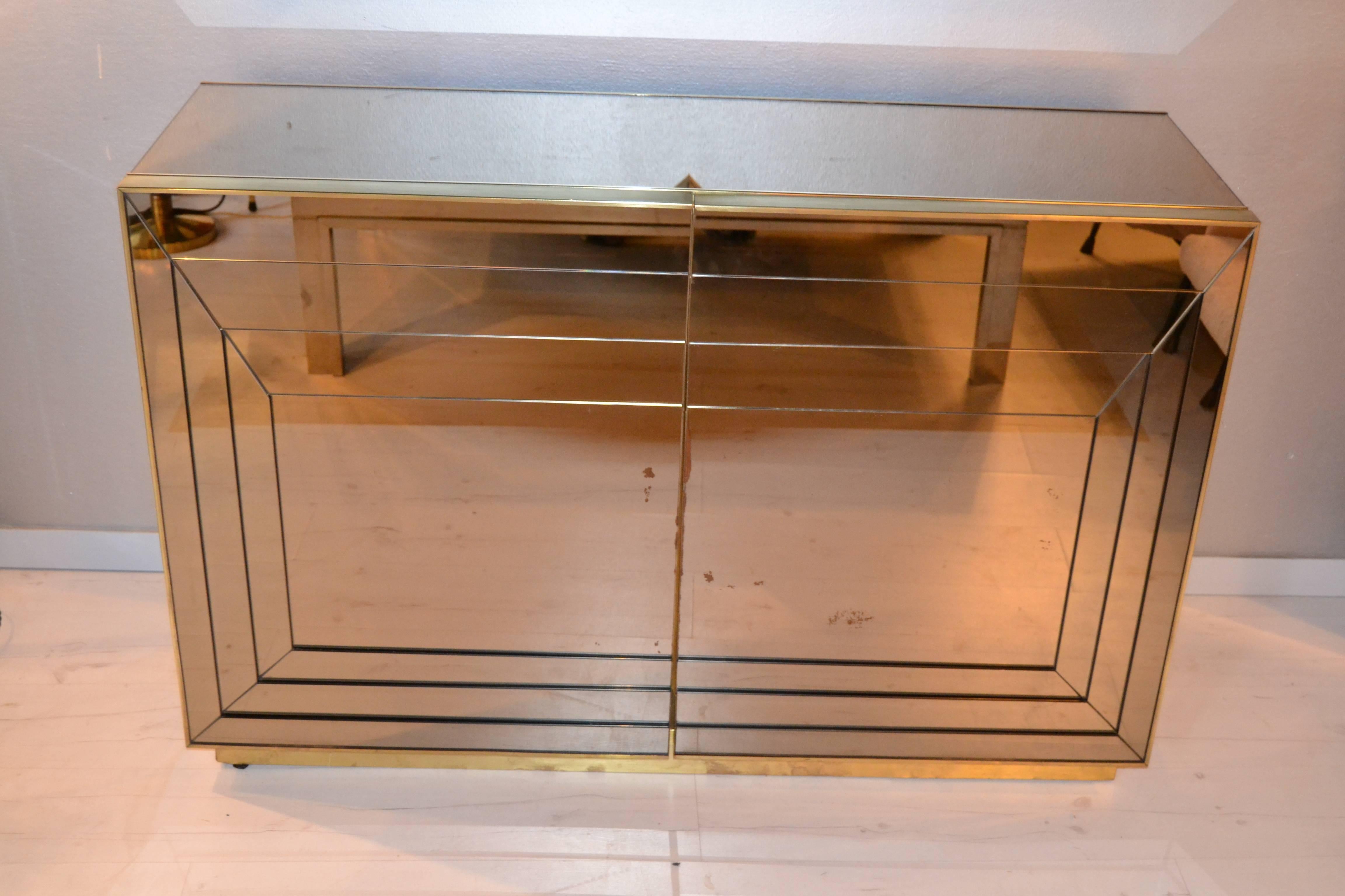 1970s bronze tinted mirrored and brass cabinet, front doors are composed by several mirror sheets. Impressive quality of manufactured.
Interior and exterior door are dress with brass details.
Two doors with one interior shelf.
Cabinet have the