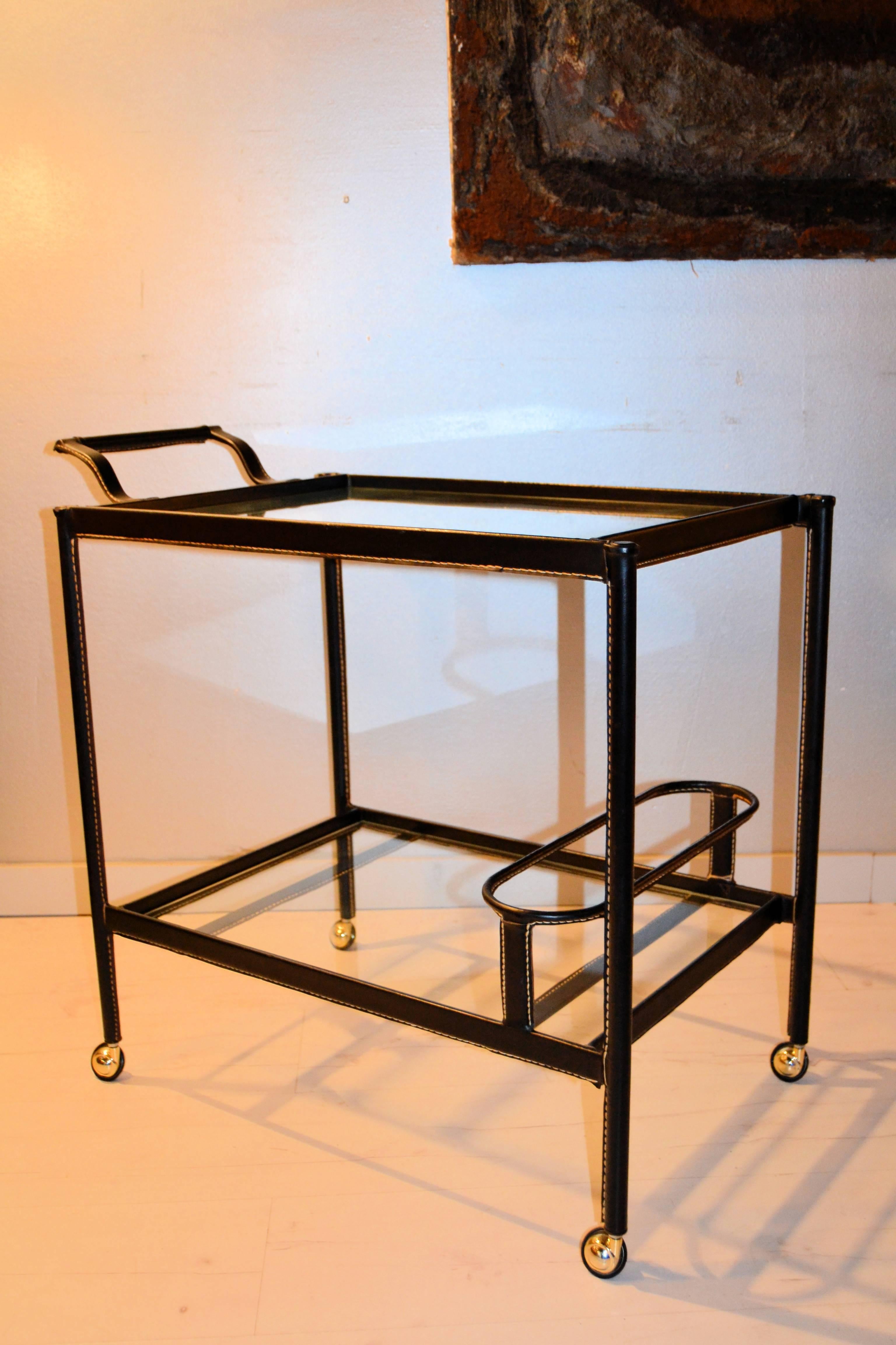 1950s Jacque Adnet black faux leather bar cart. Two glass shelf with a bottle compartment.
Accident in one of the legs as you can see in the photos.