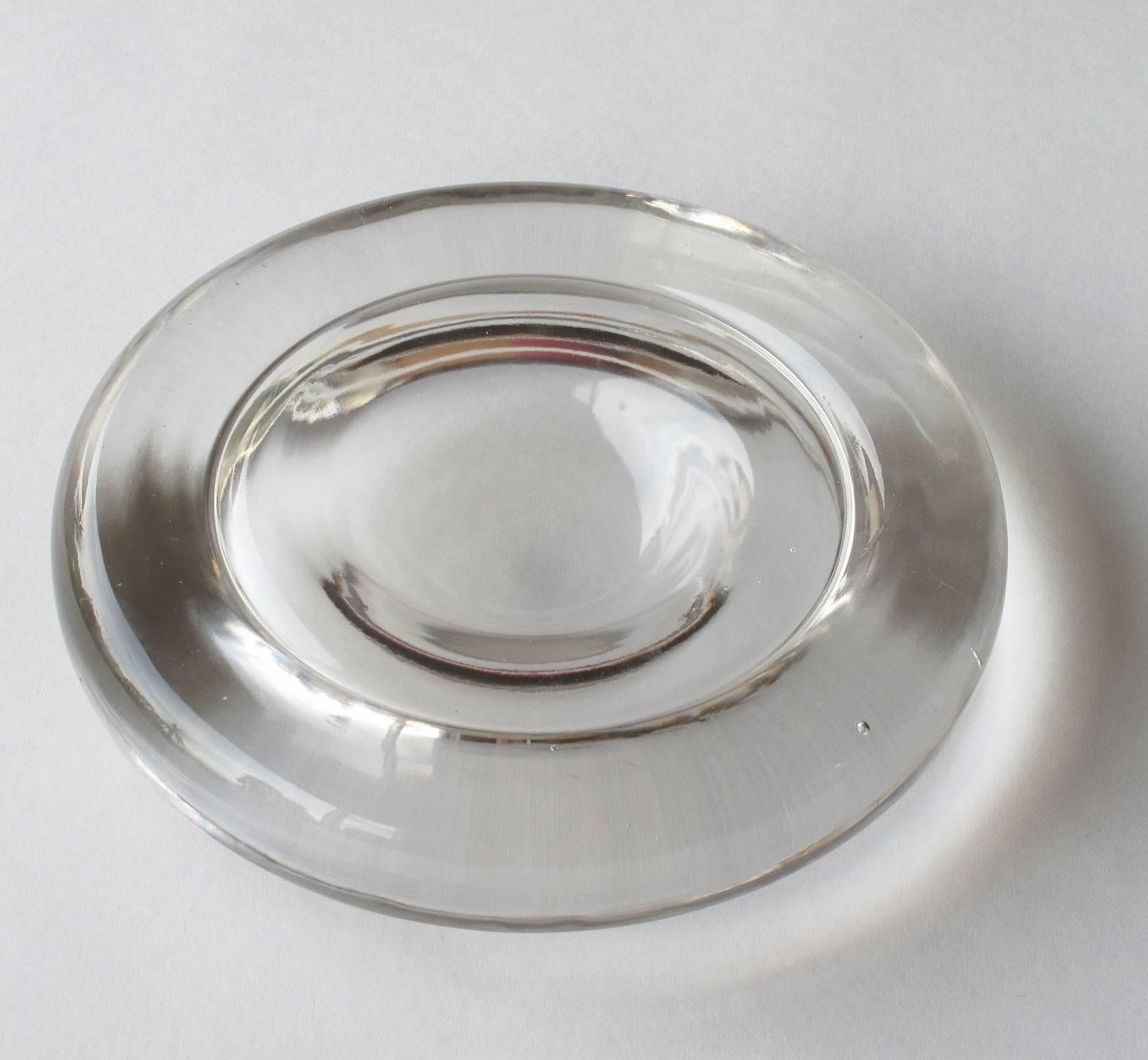 Originally designed as an ashtray, this minimal statement piece made of solid molded glass in a clear finish with a ripple shape references a single drop of water encapsulated in a moment of time. Designed by Enzo Mari and made by Danese Milano,