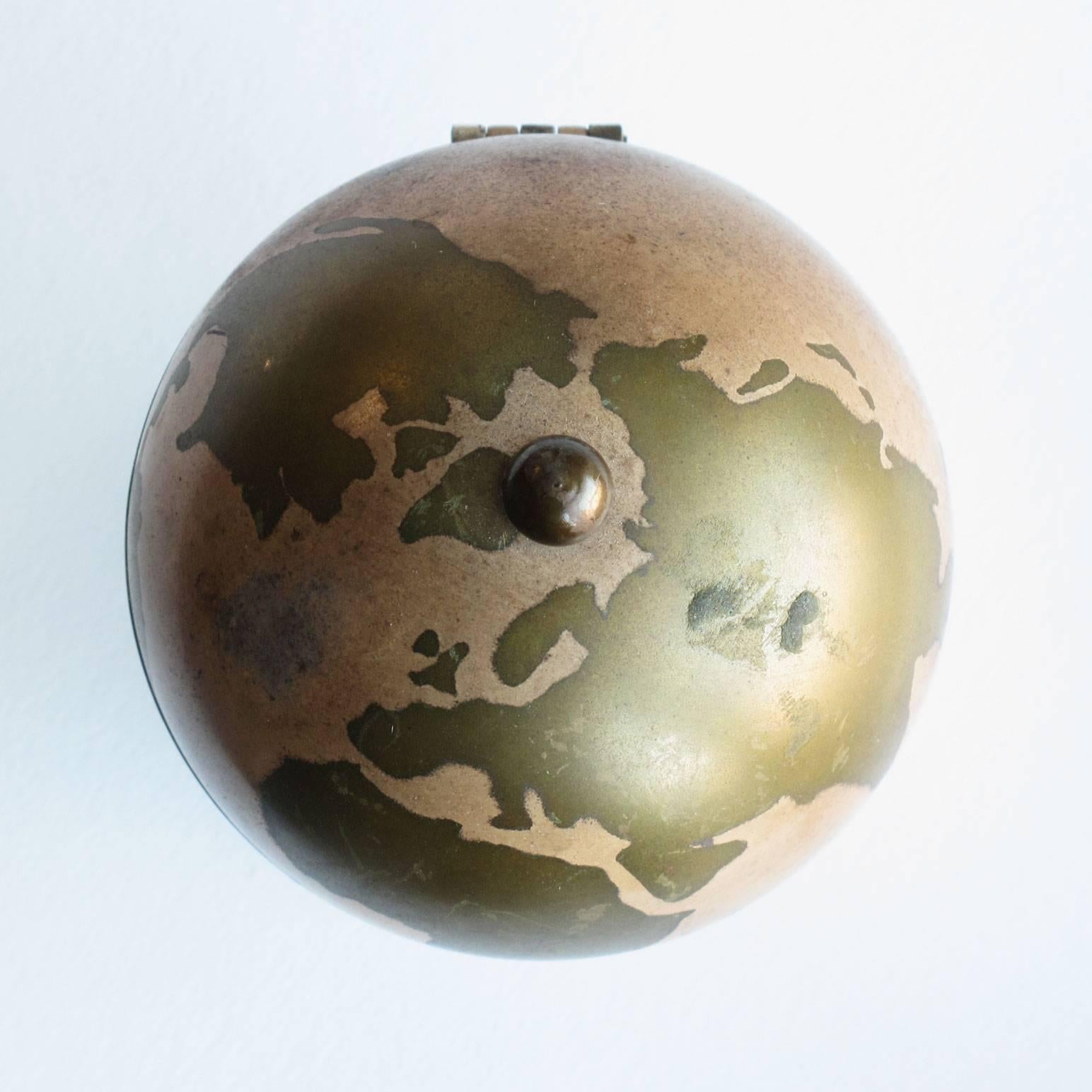 Brass decorative object with world globe design, good vintage condition with patina to surfaces. Measures: 3.5 high x 2.5 diameter.
