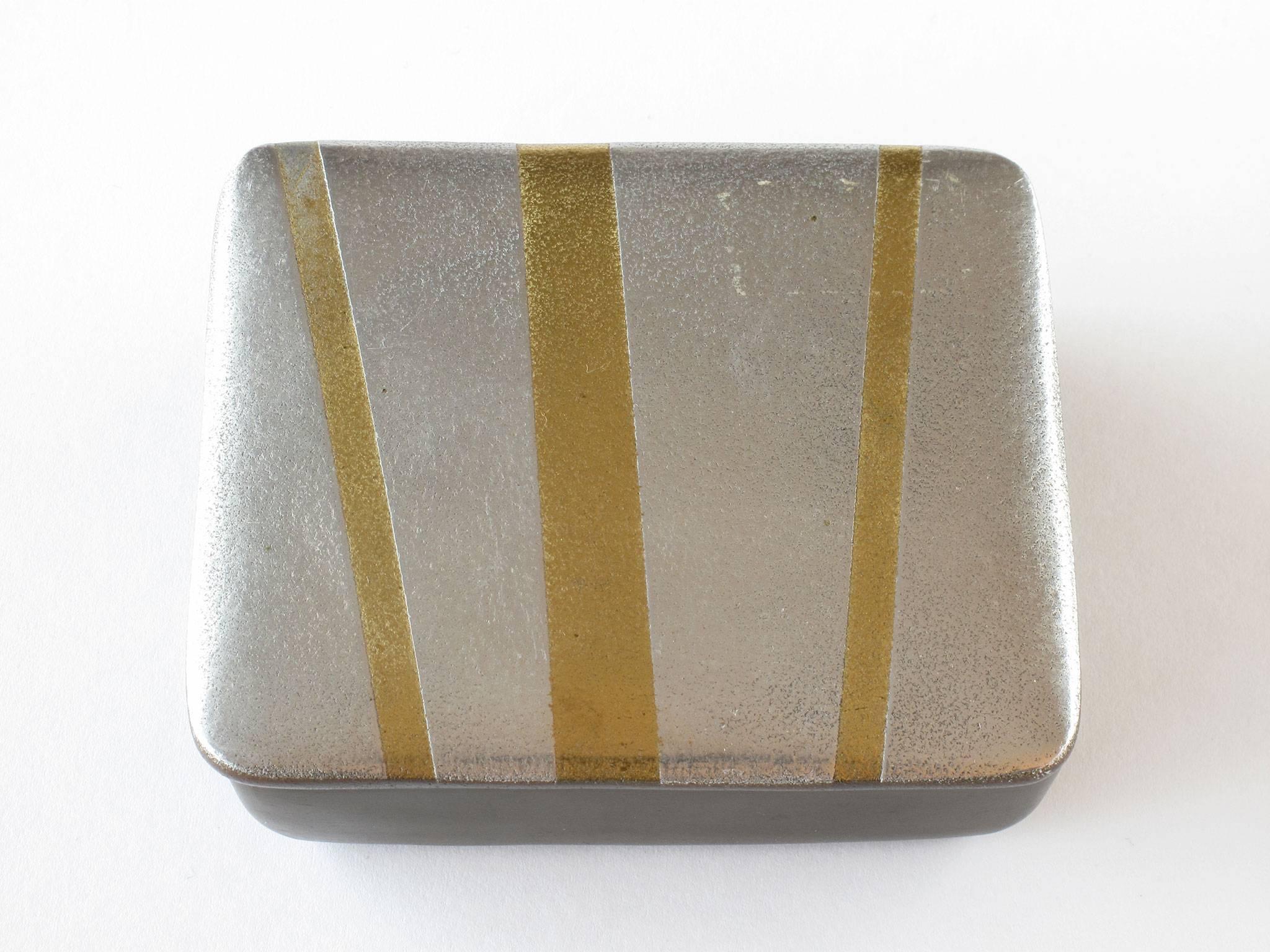 A rare design by Ben Seibel featuring his silver and gold geometric lined shapes on a dark brown enamel base, cork lined interior and felted bottom, 1950s, Jenfred Ware, New York, 1 5/8 high x 4 1/2 wide x 3 7/8 deep inches, signed, excellent