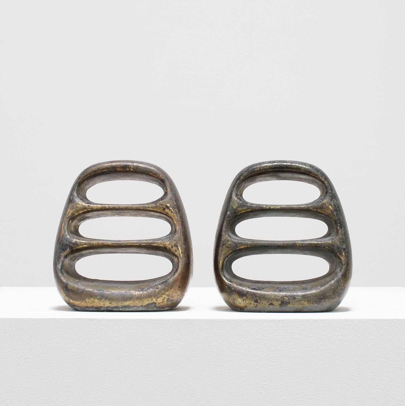 Designed by Ben Seibel and made by Jenfred Ware, New York, 1950s, a pair of bookends in brass plated cast metal displaying heavily patinated surfaces as if they were cast into the salty fathoms of the bay, similar to the Flame Collection Chair