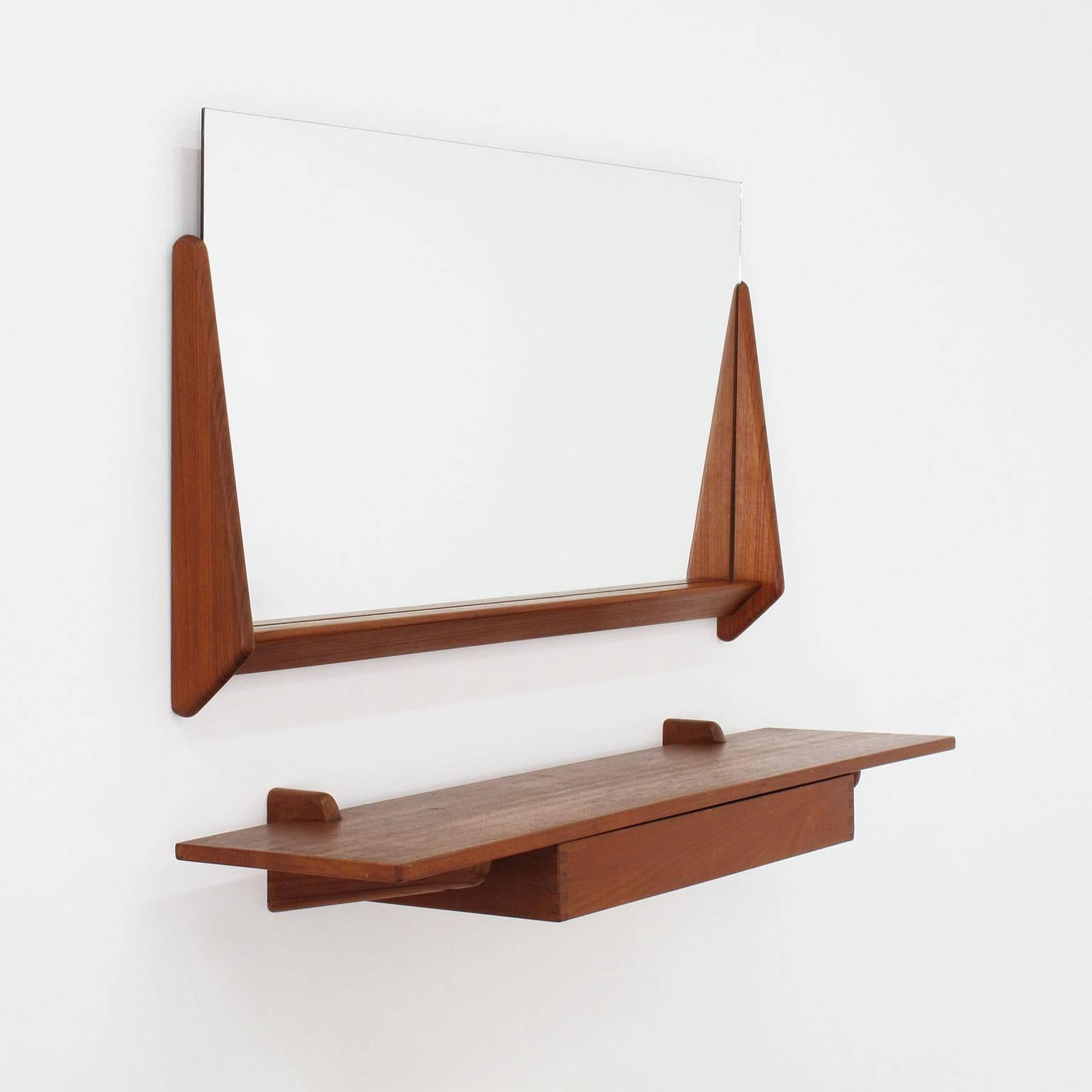 Aksel Kjersgaard
Designed wall mirror and floating shelf
Solid teak, made in Denmark
Odder, 1960s
Dimensions of mirror and frame in inches: 18 high x 32.38 wide x 3 deep
Dimensions of mirror alone in inches: 15.5 high x 31.5 wide
Dimensions of