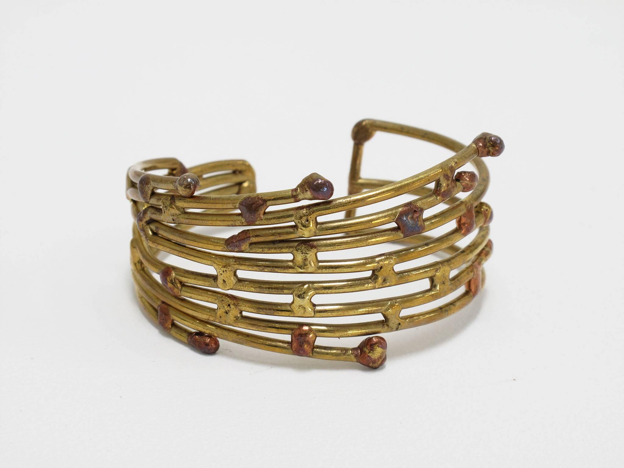 This antique piece of jewelry, hand-sculpted in brass and accented by drops of copper, Modernist in style and Brutalist in technique, fits comfortably on a smaller wrist and arm, 1 1/4 high x 3 wide x 2 1/4 deep inches.