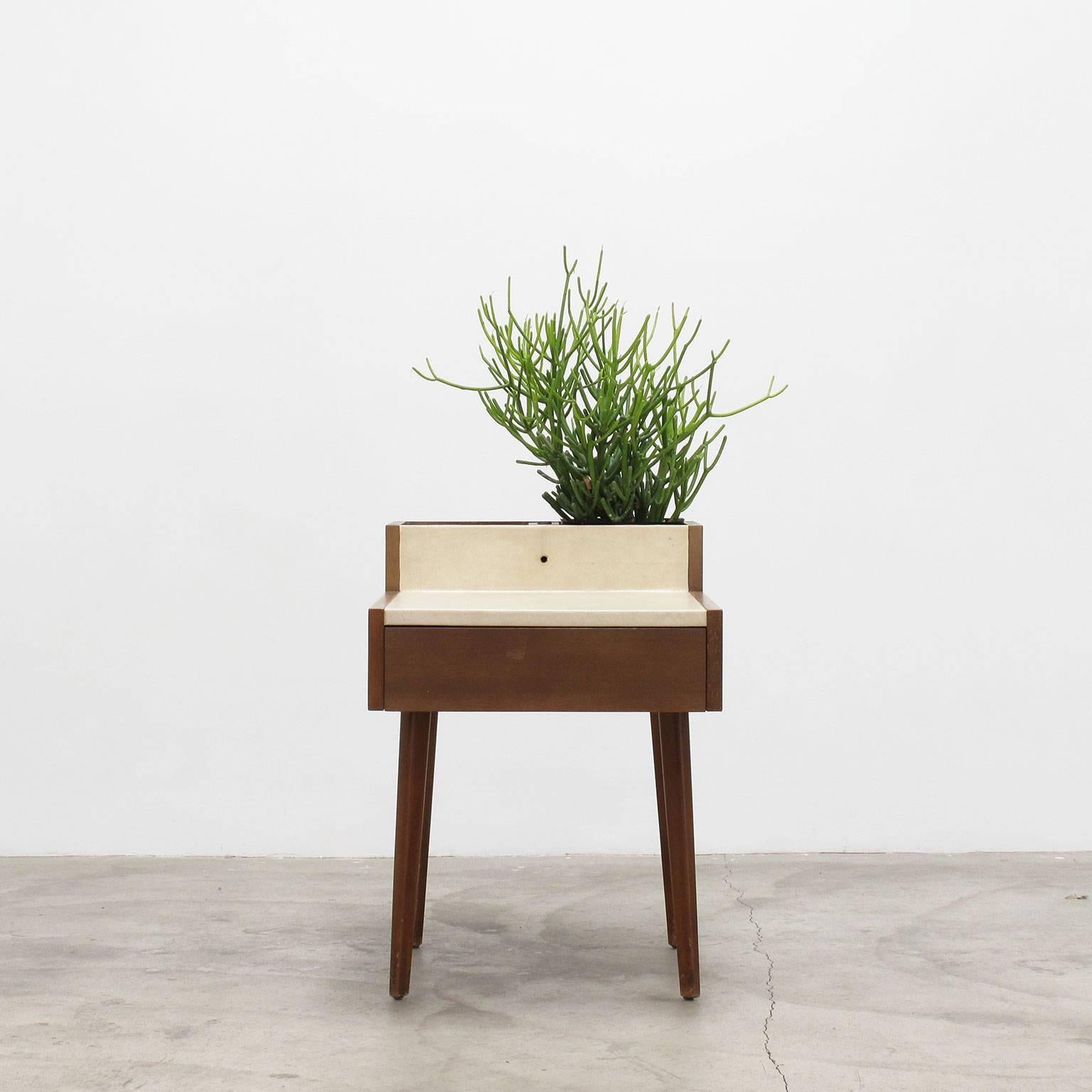 George Nelson
Planter table, 1950s
Herman Miller

Iconic side table in walnut with cream white leather wrapped top surface, finely tapered legs, slightly splayed, and two square compartments with original copper plant boxes, interior of drawer