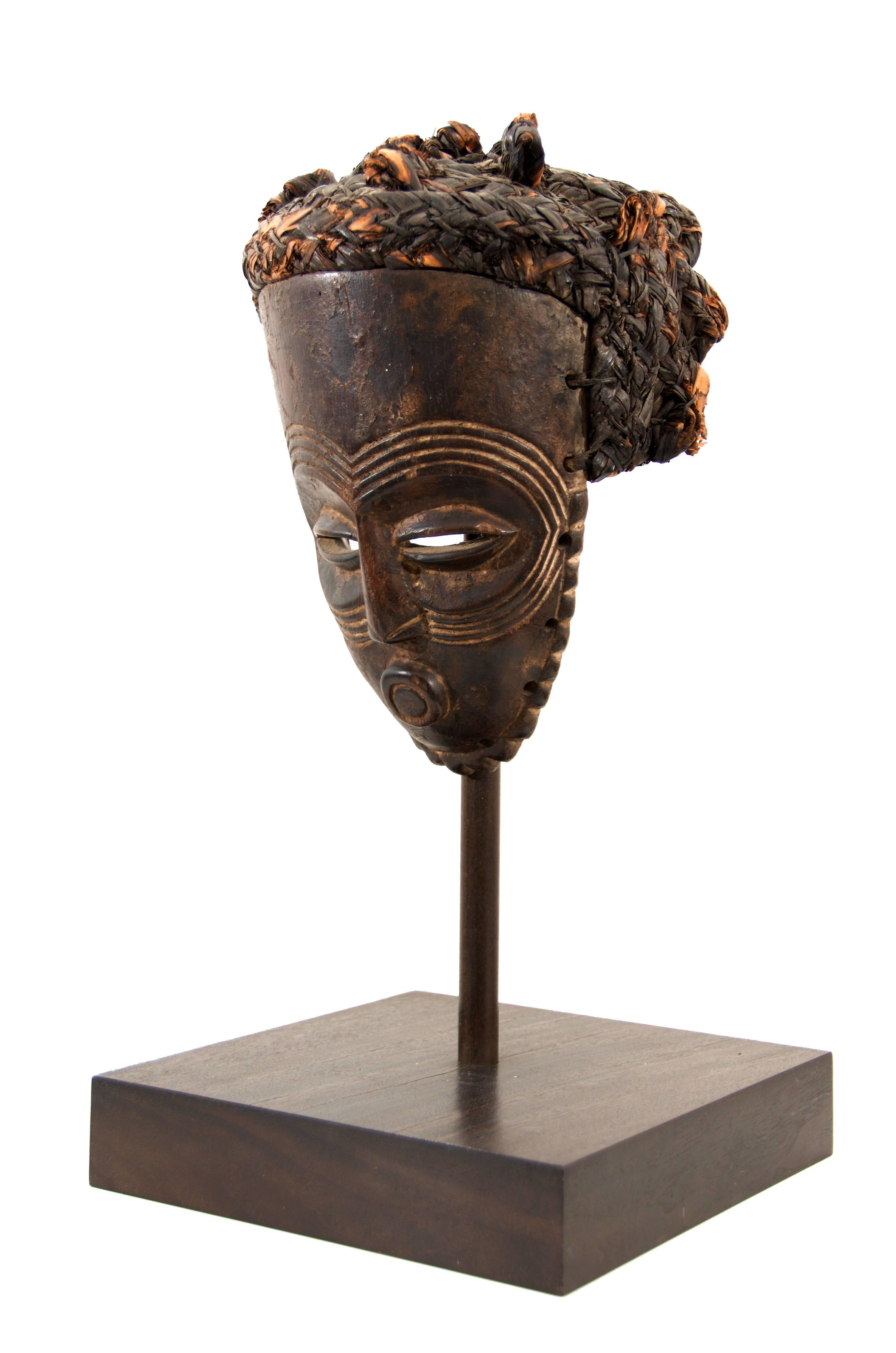 Carved wood tribal mask from the Baule Tribe, West Cost of Africa. Early 20th century. Mounted on custom wood plinth.