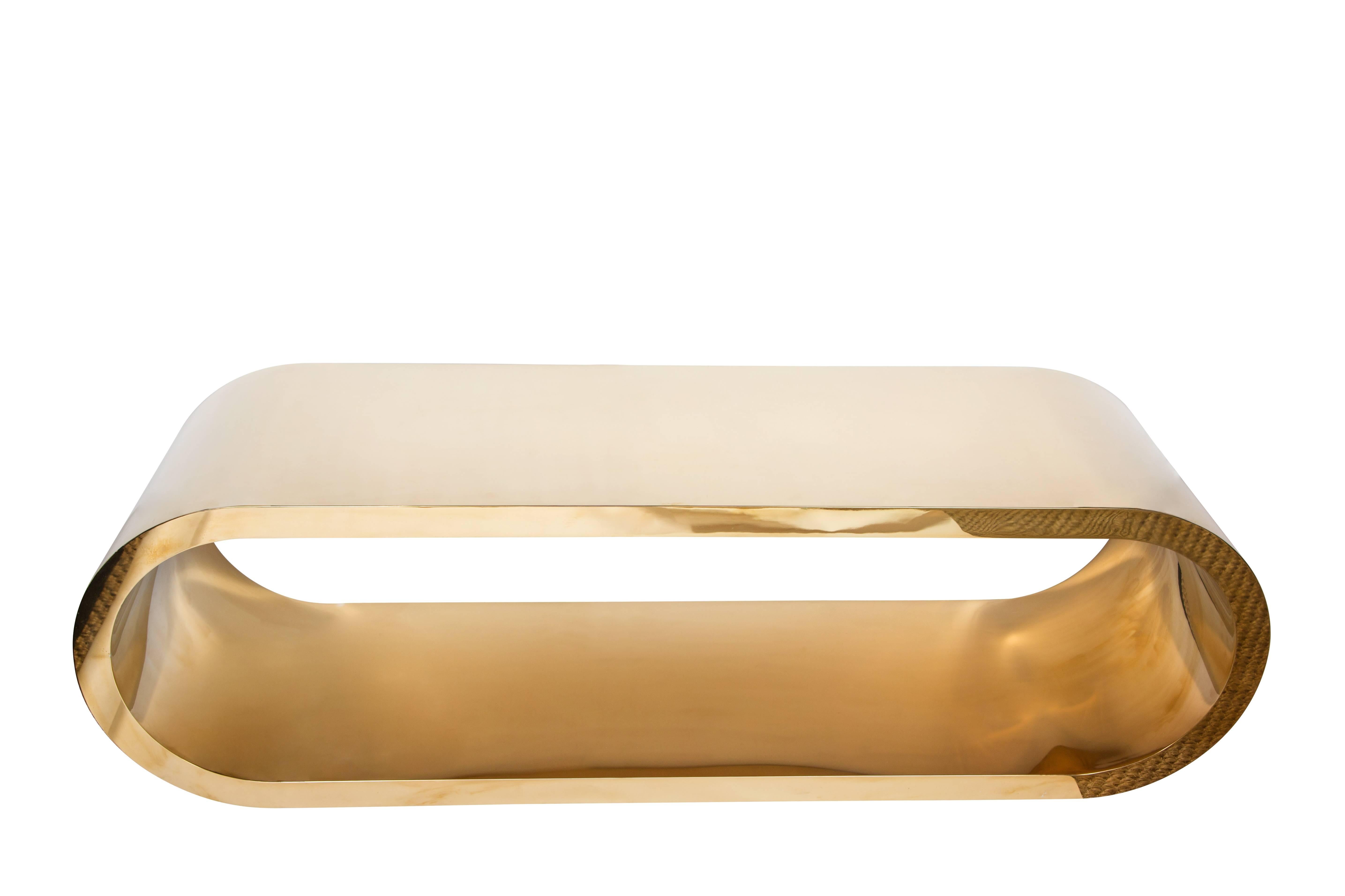 Sculptural coffee table in an elliptical shape clad in polished brass. Coffee table is reminiscent of the style of Pierre Cardin.  Late 1980s.