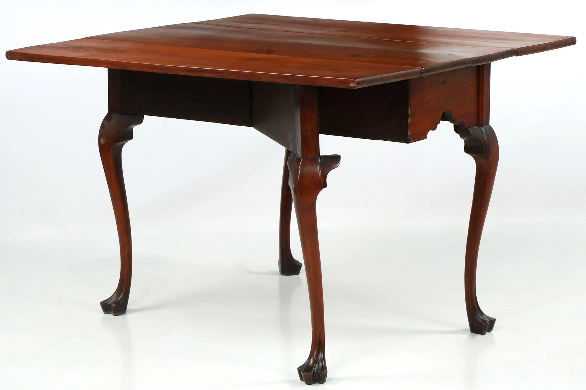 This pure and incredibly beautiful wslnut drop-leaf table is a rare and cherished treasure - clearly owned by a family that cared for it, the table remains in pristine condition with a very early refinish that has since grown a deep and lovely