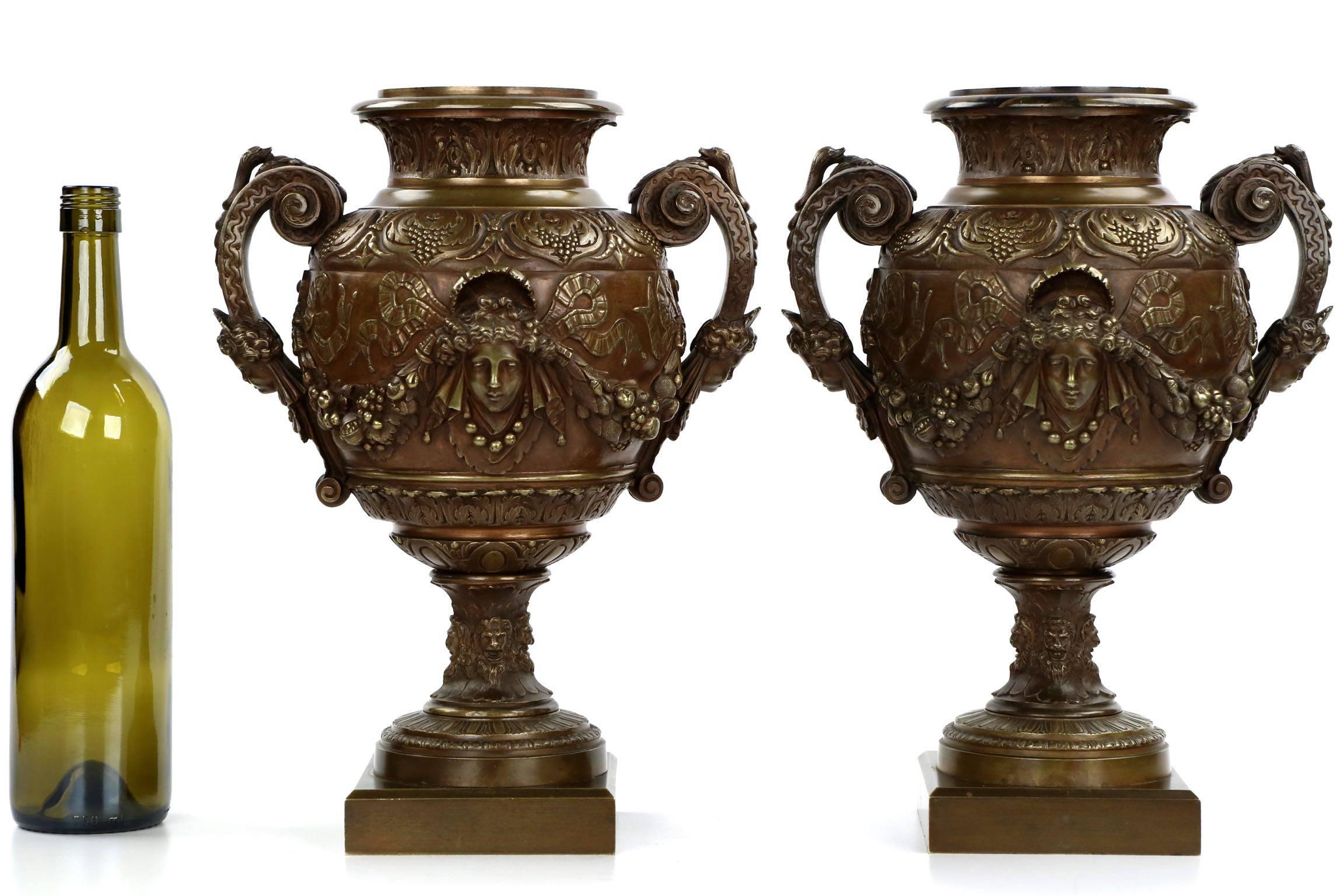 A powerful pair of vases with intricate classical castings set symmetrically across all surfaces, these are a most fine strikepoint for a mantel or hallway console.  The female masks on either side are flanked by furls of twisting ribbon that