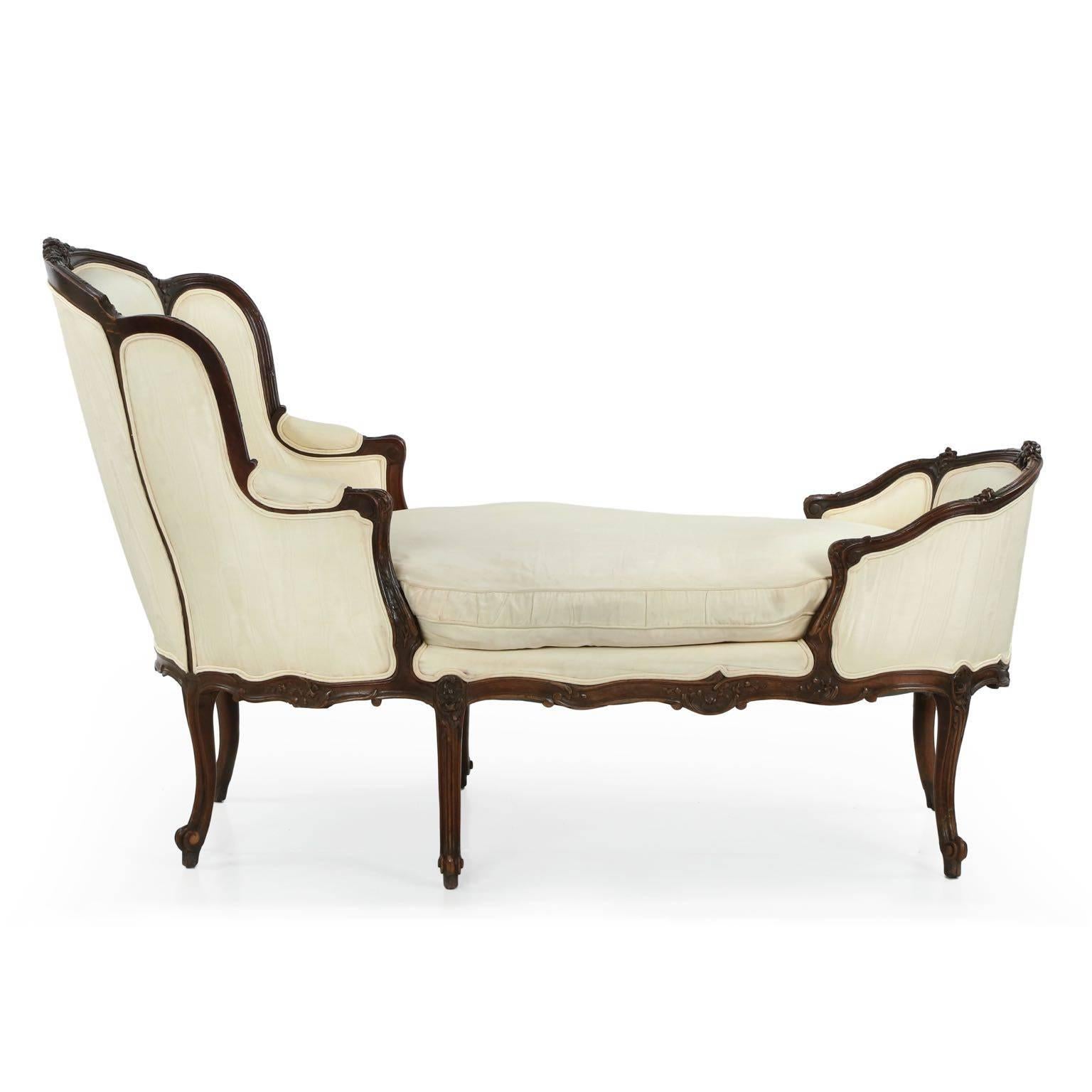 Noteworthy for it’s petite and overall delicate proportions, this very attractive chaise longue is crafted in the Louis XV taste probably during the last quarter of the 19th century. The dark walnut frame is handsomely carved with floral displays in