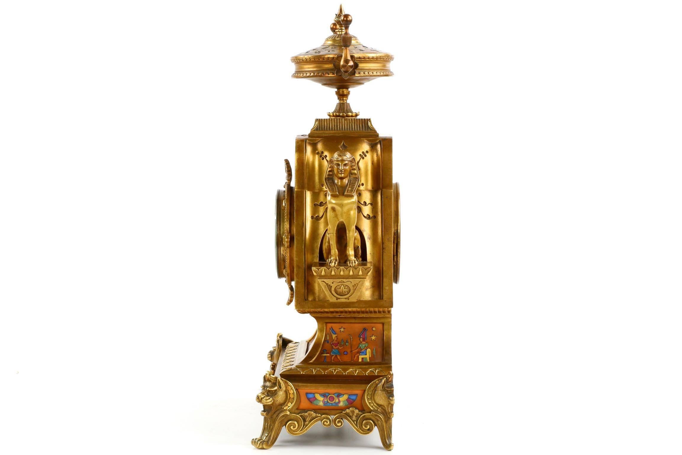 A work of an unusually whimsical Egyptian inspiration, this exceedingly fine matched candelabra and clock set exhibit powerful pictorial scenes of priests, enthroned royalty, the stylized animal depictions and other naturalistic interpretations of