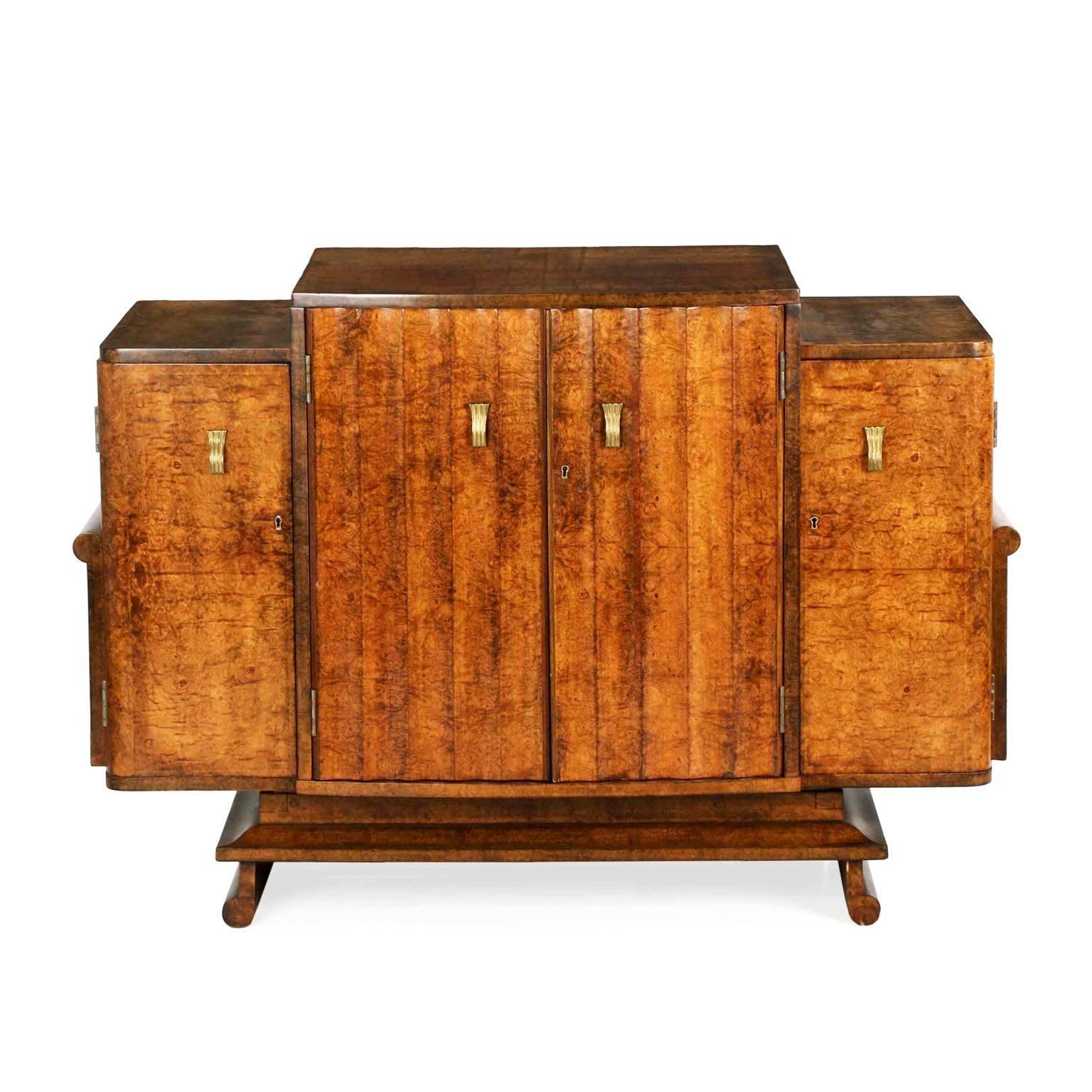 A most interesting and imaginative piece, this fine amboyna veneered console features a stepped top with a pair of central doors with a repeating cove form that is opposed in the outward curls of the vertical planes on either side of the console and