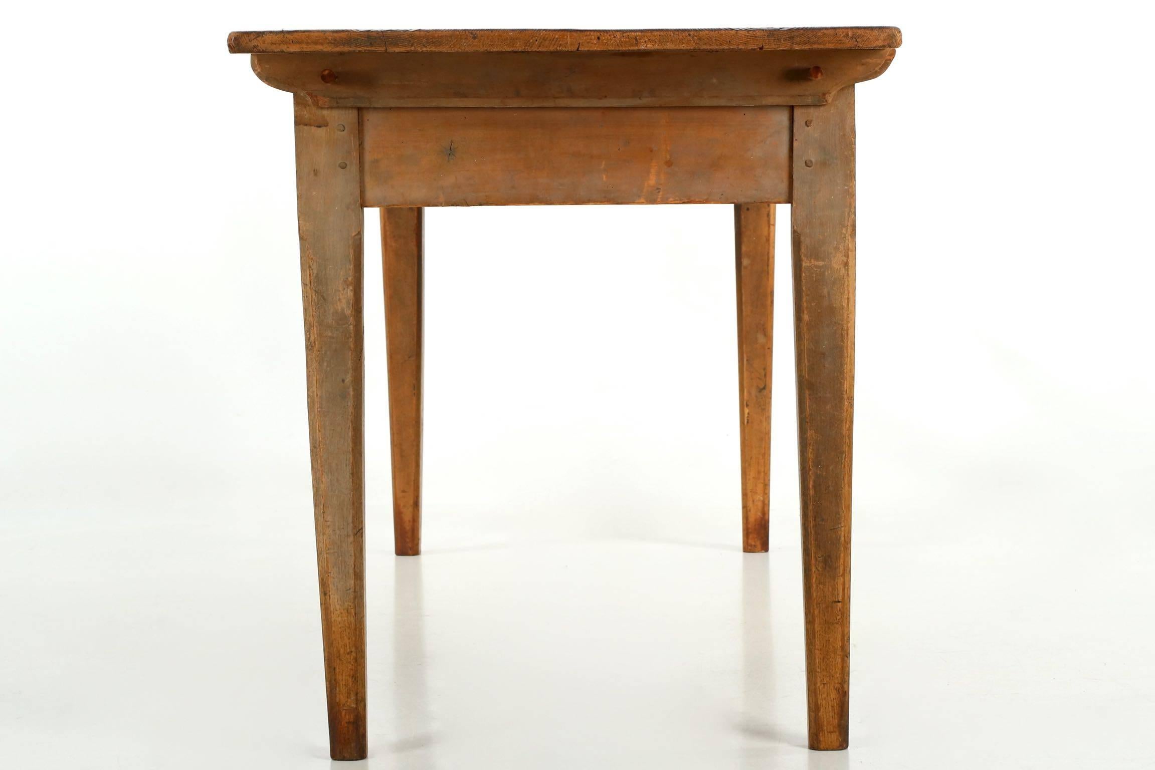 Entirely original and beautifully worn, this harvest table retains an old and complex ochre washed surface with hints of gray, these well over a century old and just gorgeous. The structure is simple and effective, the apron tenoned into the legs