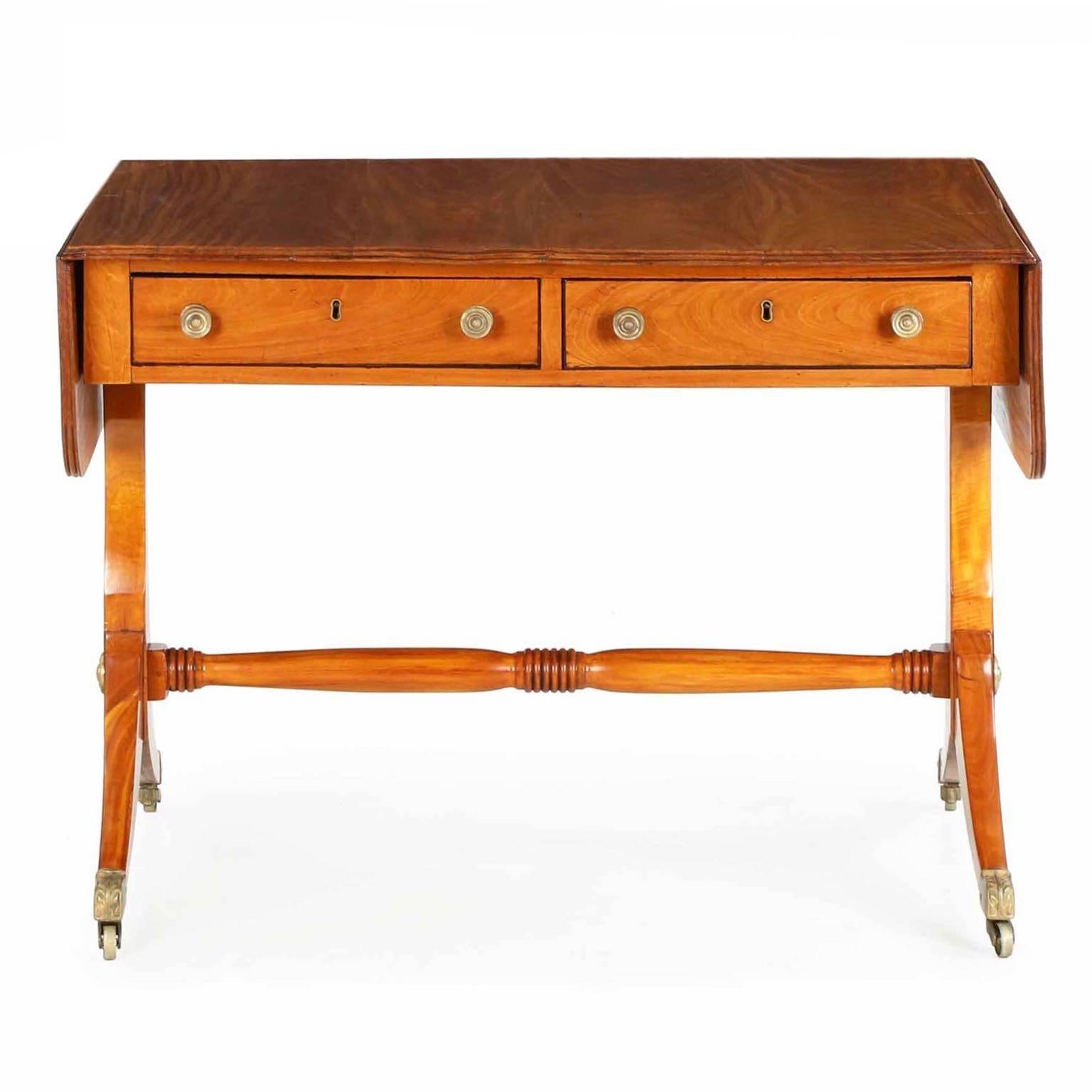 Refined and elegant in every way, this superb Regency sofa table is crafted with the coveted, hard to acquire and expensive satinwood. Most often used in stringer inlay and in veneers due to the sheer cost of the unusual plank, the majority of