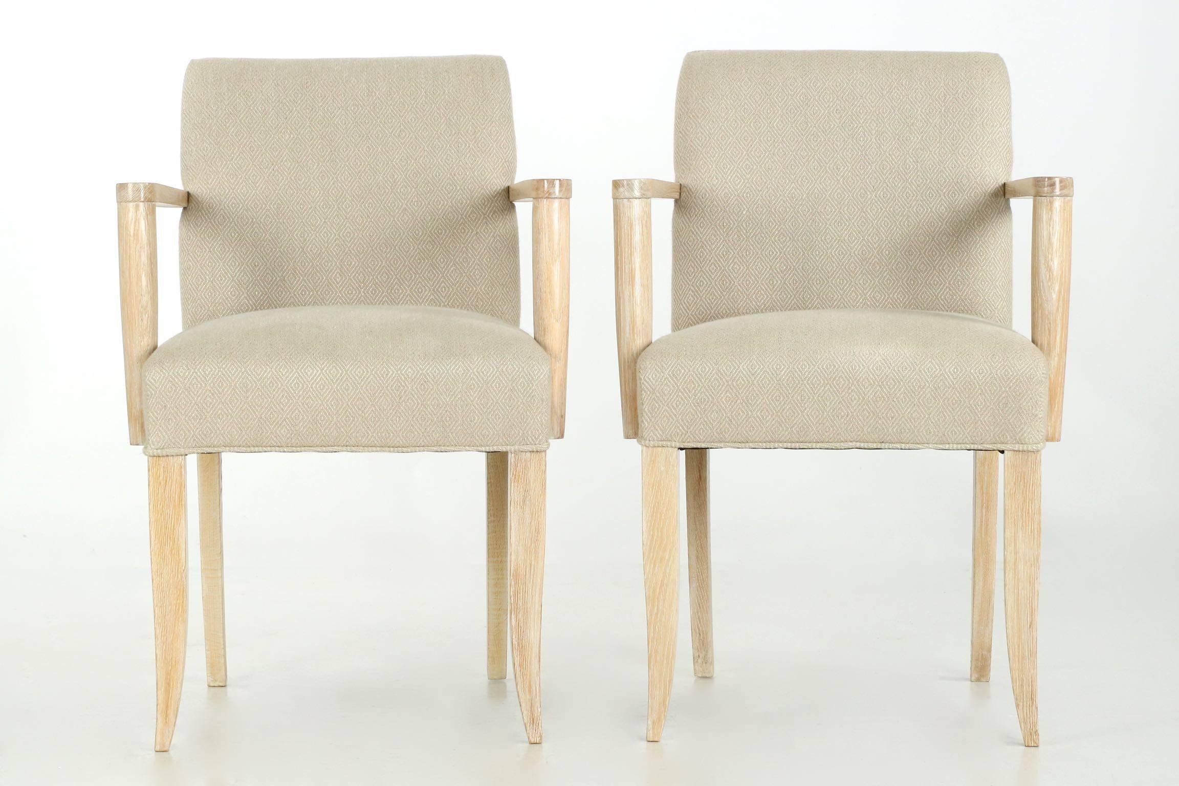 Incredibly pleasing in every sense, this fine pair of French modern cerused oak arm chairs is upholstered in a patterned woven tweed that is deeply comfortable. Crisp in lines and crafted with skill, they are quite sturdy and built to last