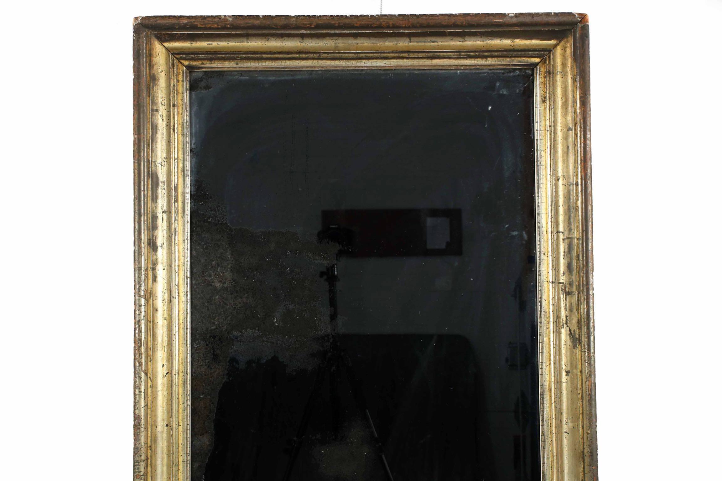 This is such an interesting and beautifully worn piece, retaining much of its original burnished gilding, now oxidized with a slowly developed patina throughout, the frame is noteworthy for its sheer austerity. A simple cove molding surrounds the