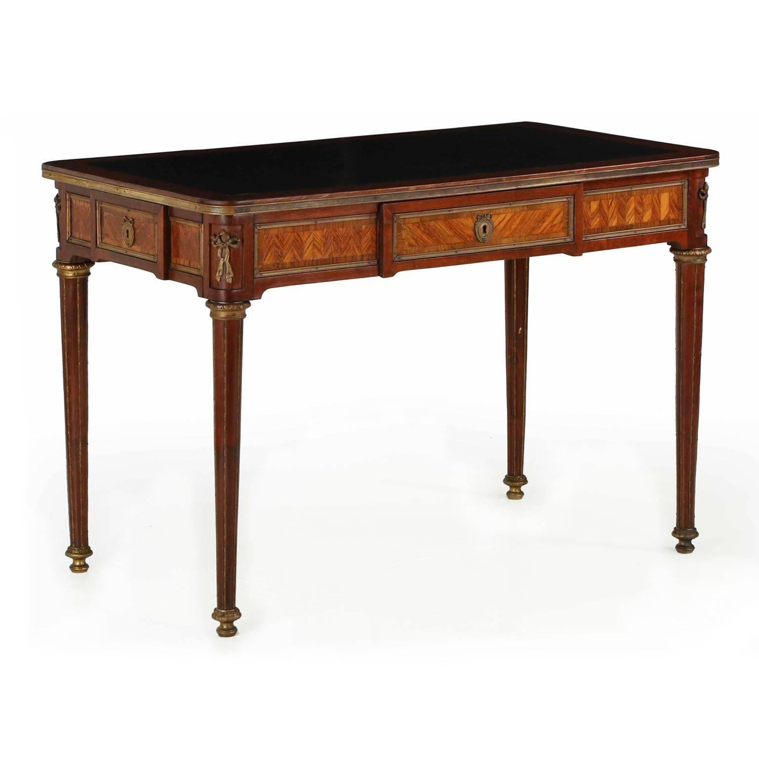 A most attractive writing table from the second quarter of the 20th century, this desk was crafted in the Louis XVI taste using exotic kingwood veneers laid out in an angular parquetry across each panel of the apron. The effect against the dark
