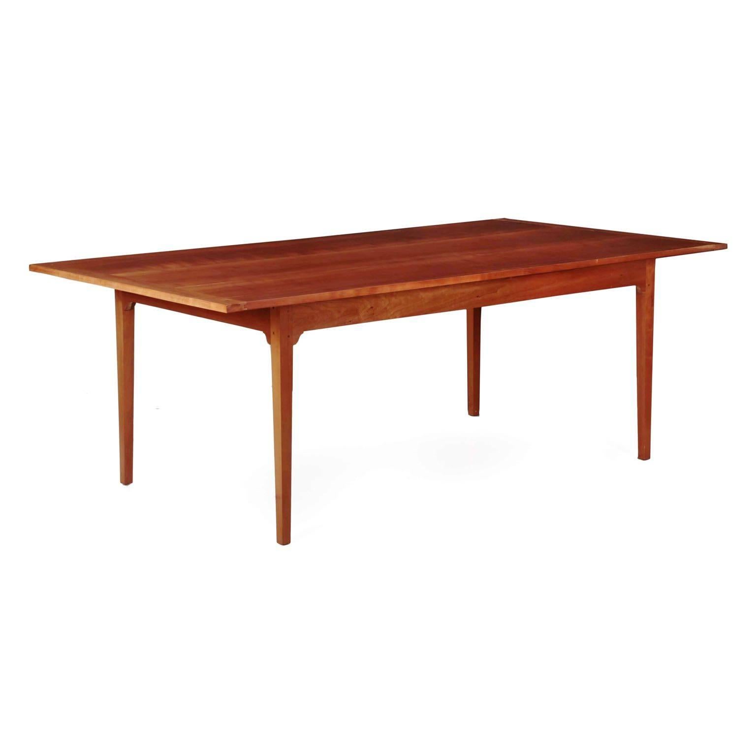 A carefully handmade custom table executed in solid cherrywood, the dining table is austere and orderly in its’ clean lines and angular form. The long boards are capped with breadboard ends with small pins affixing the tongue-in-groove joints. The