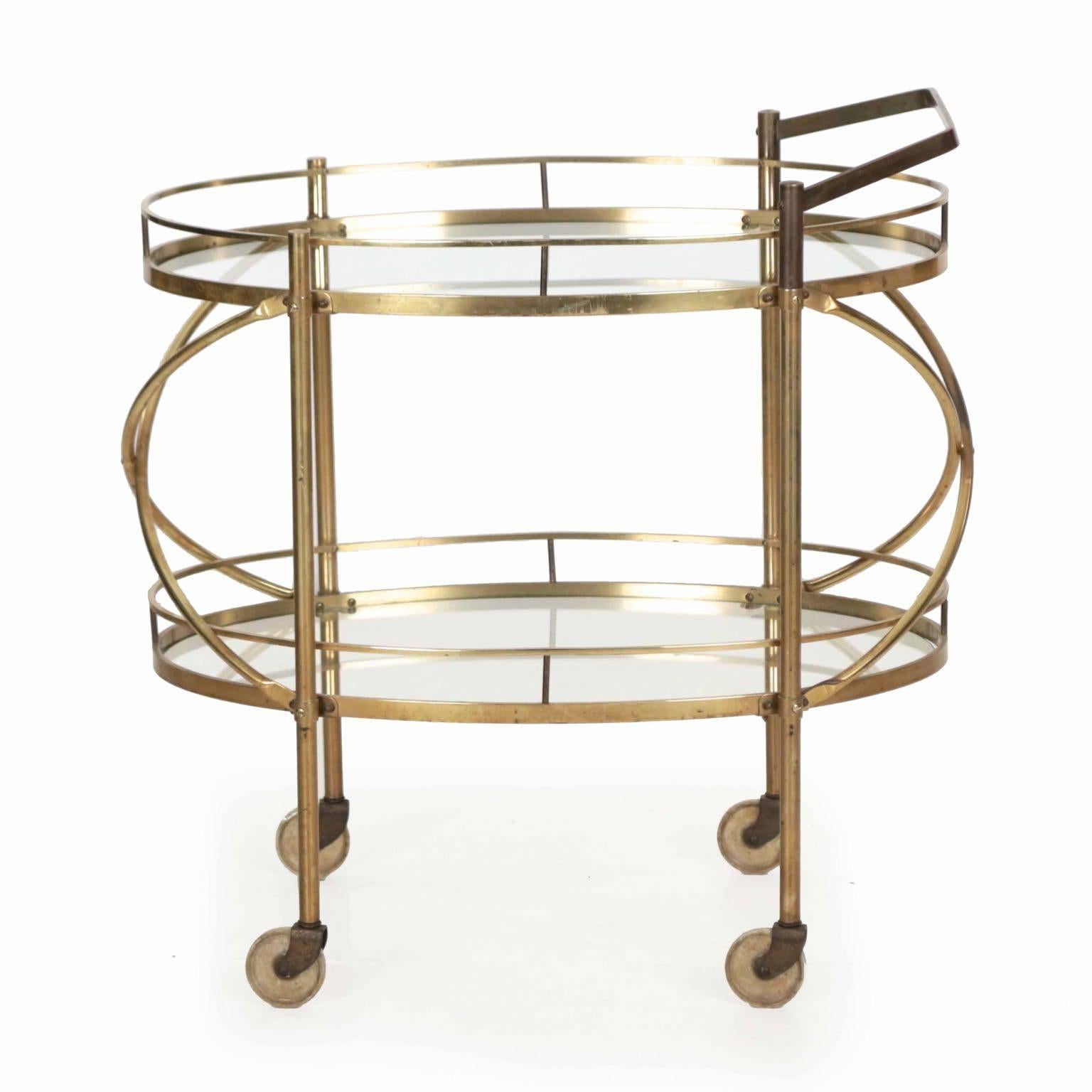 A very nice brass and glass serving bar cart from the 1960s with precise and high quality metal work throughout, the form is unsigned but very similar to some of the pieces by Maxwell Phillips of New York, though generally without the bent tubular