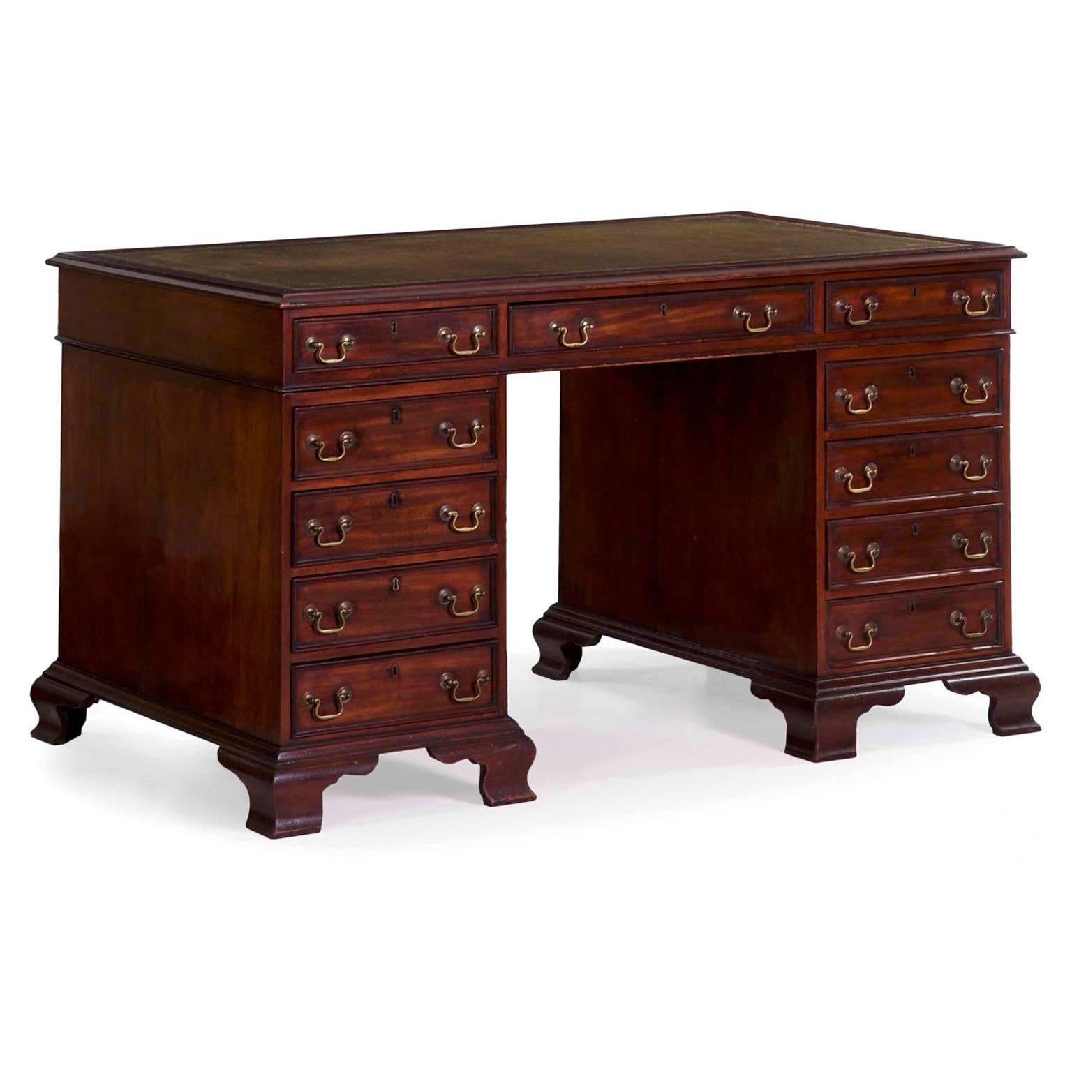 A beautiful presentation with its old and deeply oxidized surface, the desk has lovely hue variation from vibrant red mahogany to dark browns and fading into nearly black in the deepest crevices and corners. It retains the original gilt-tooled green