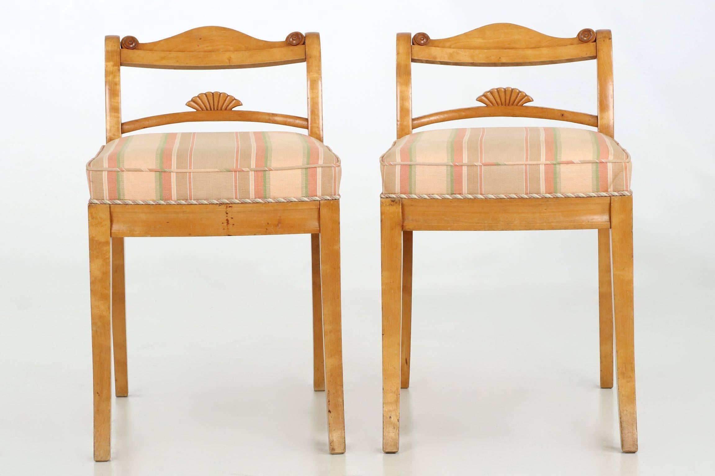 An unusual and most striking pair of low back side chairs from the first quarter of the 20th century, they reflect the austere yet whimsical taste of the Biedermeier period in the simple birch woods and interesting splat carvings. A smooth curvature