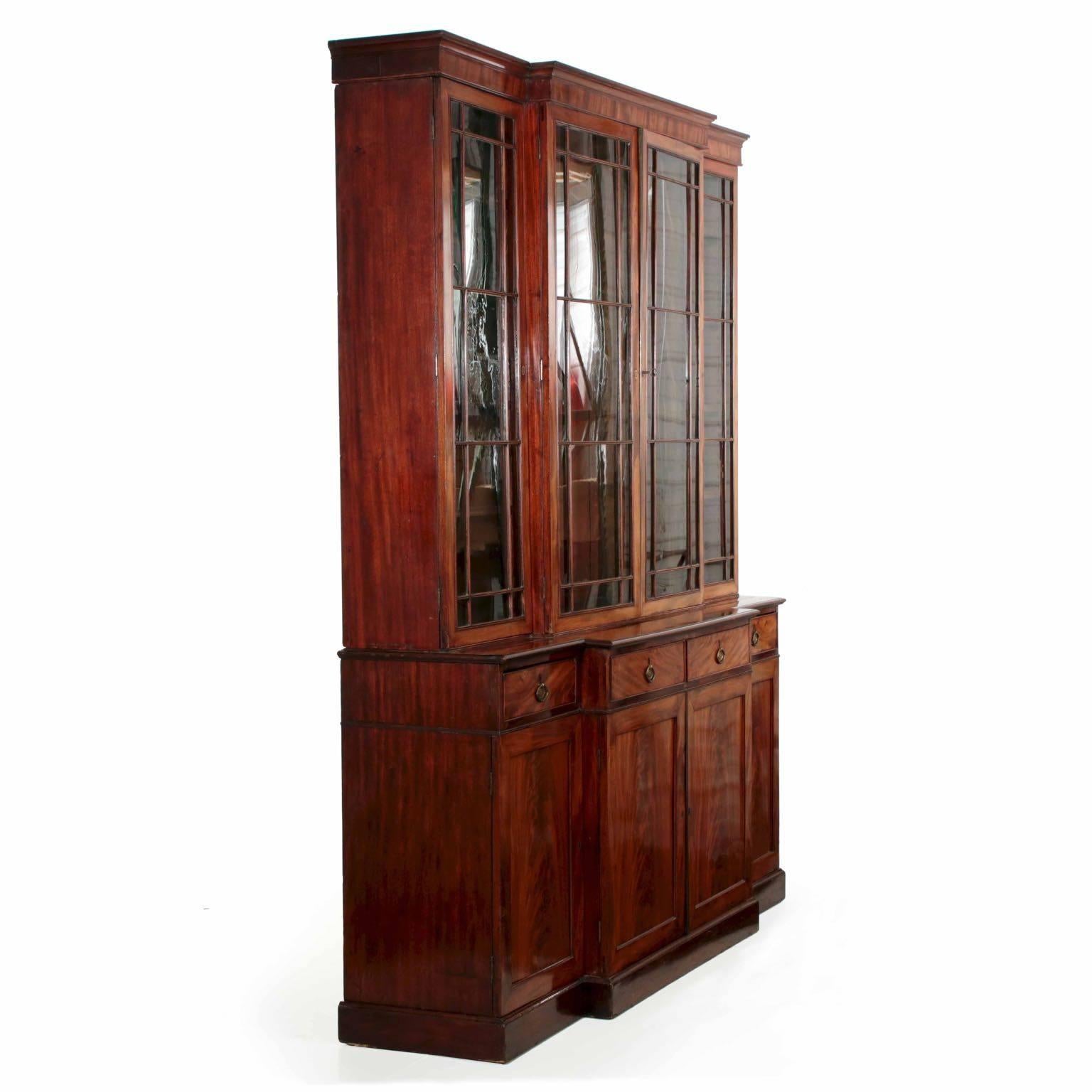 An exquisite piece of careful craftsmanship, this fine breakfront exhibits precision and perfect symmetry with most excellent timbers throughout. Crotch-mahogany planks are selected for the doors, likely all cut from the same plank; the drawers are